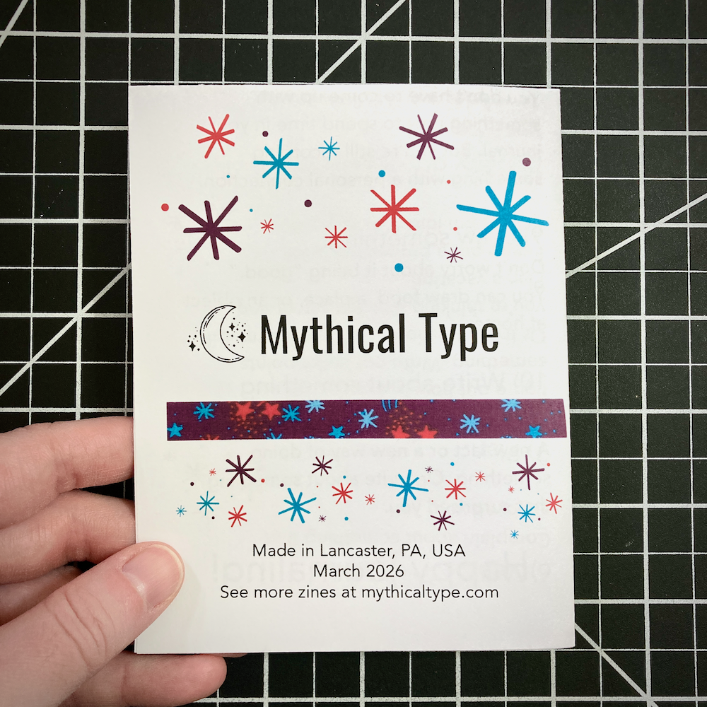 A hand holds a Mythical Type zine decorated with colorful starbursts, over a black and white grid background.