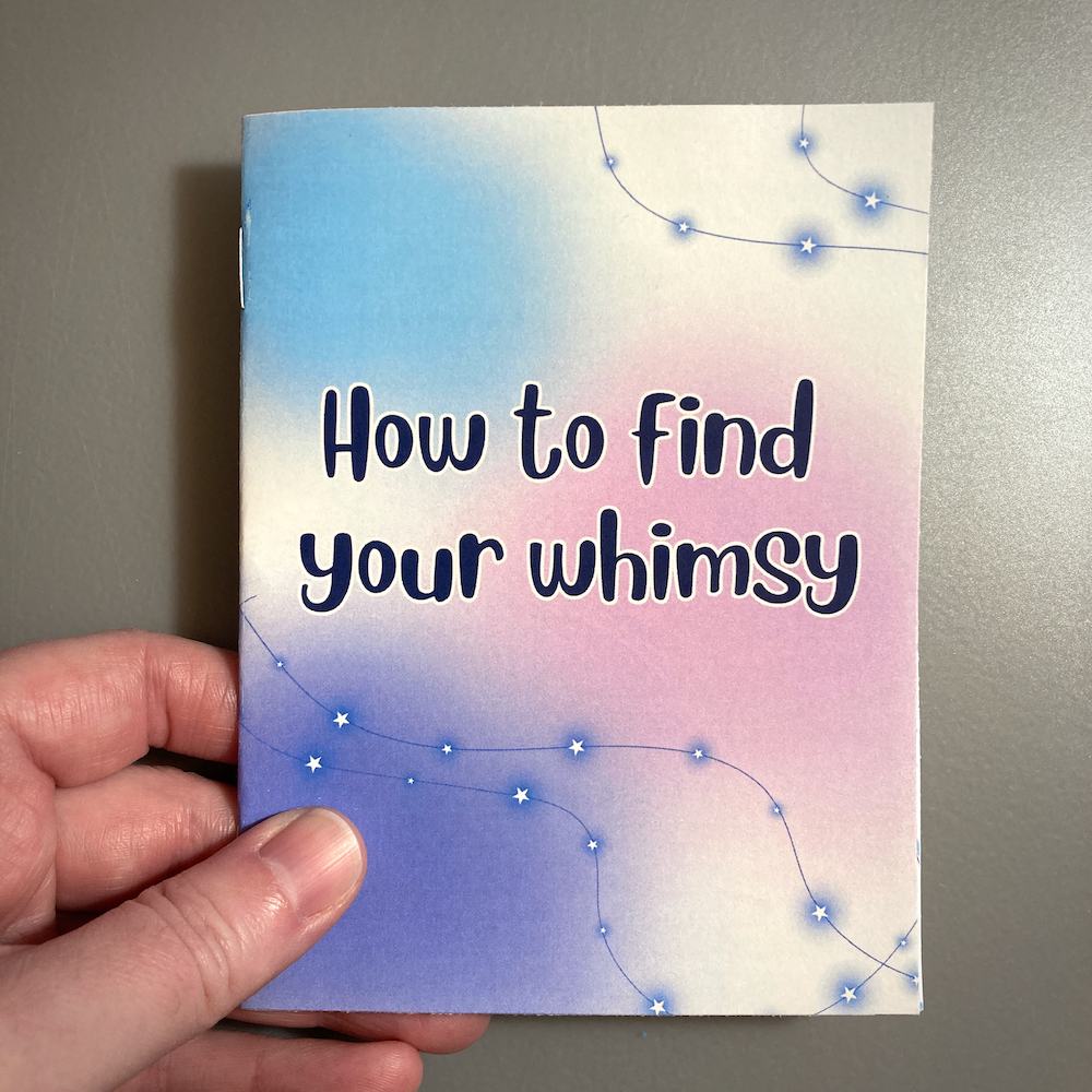 A hand holds a booklet titled How to find your whimsy, featuring a pastel gradient background with constellation-like designs.