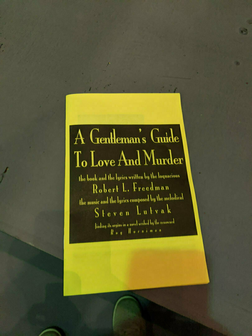 A book with a yellow cover titled A Gentleman's Guide to Love and Murder is laying on a flat surface.
