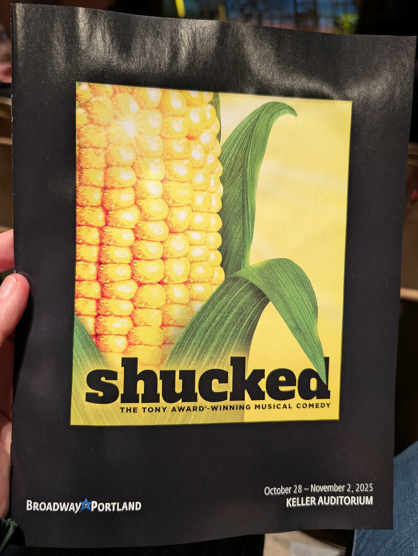 A program cover features an image of corn with the title Shucked for a Tony Award–winning musical comedy at Keller Auditorium.