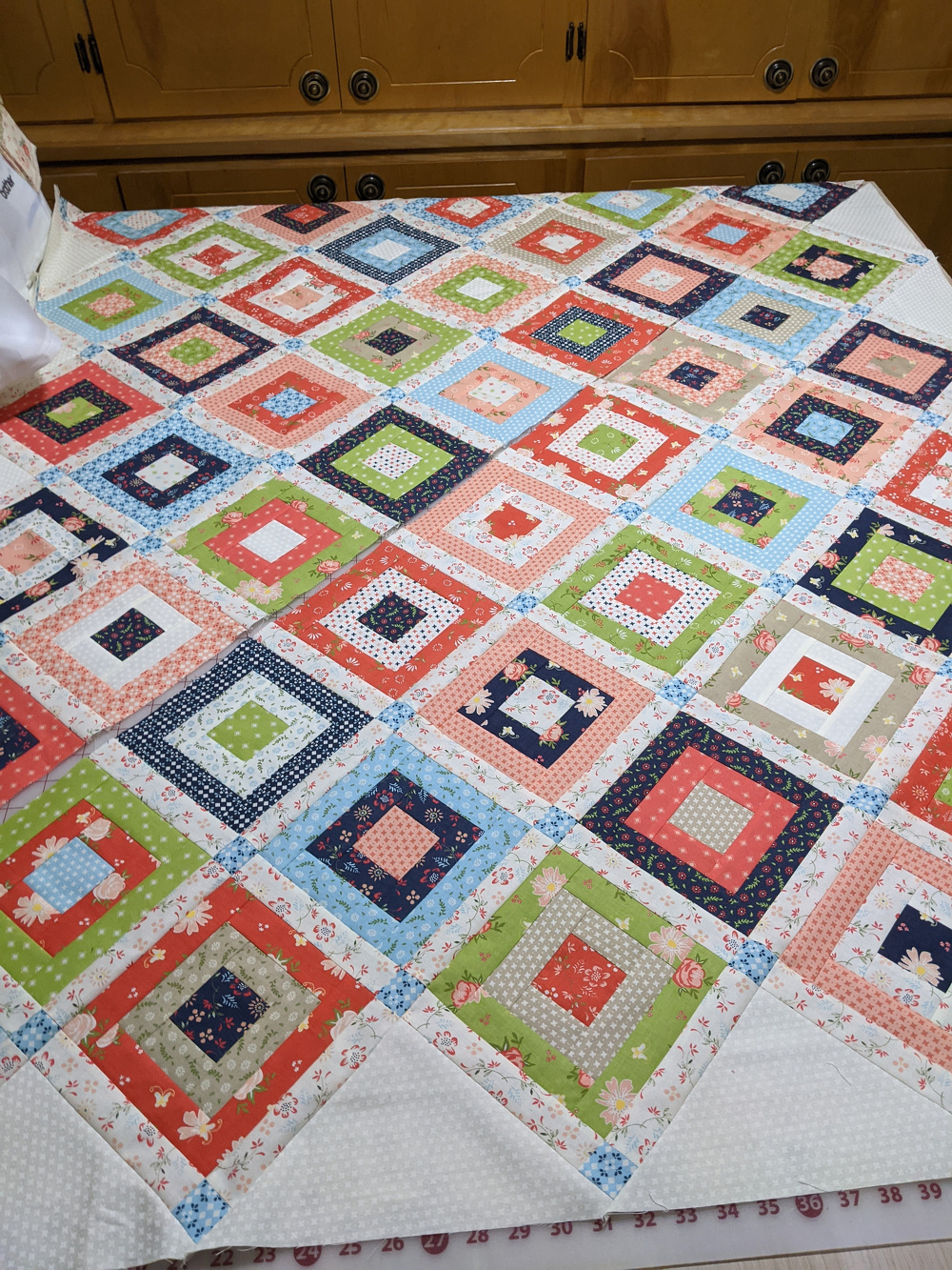A colorful quilt features a pattern of squares in various fabrics, arranged neatly on a bed.