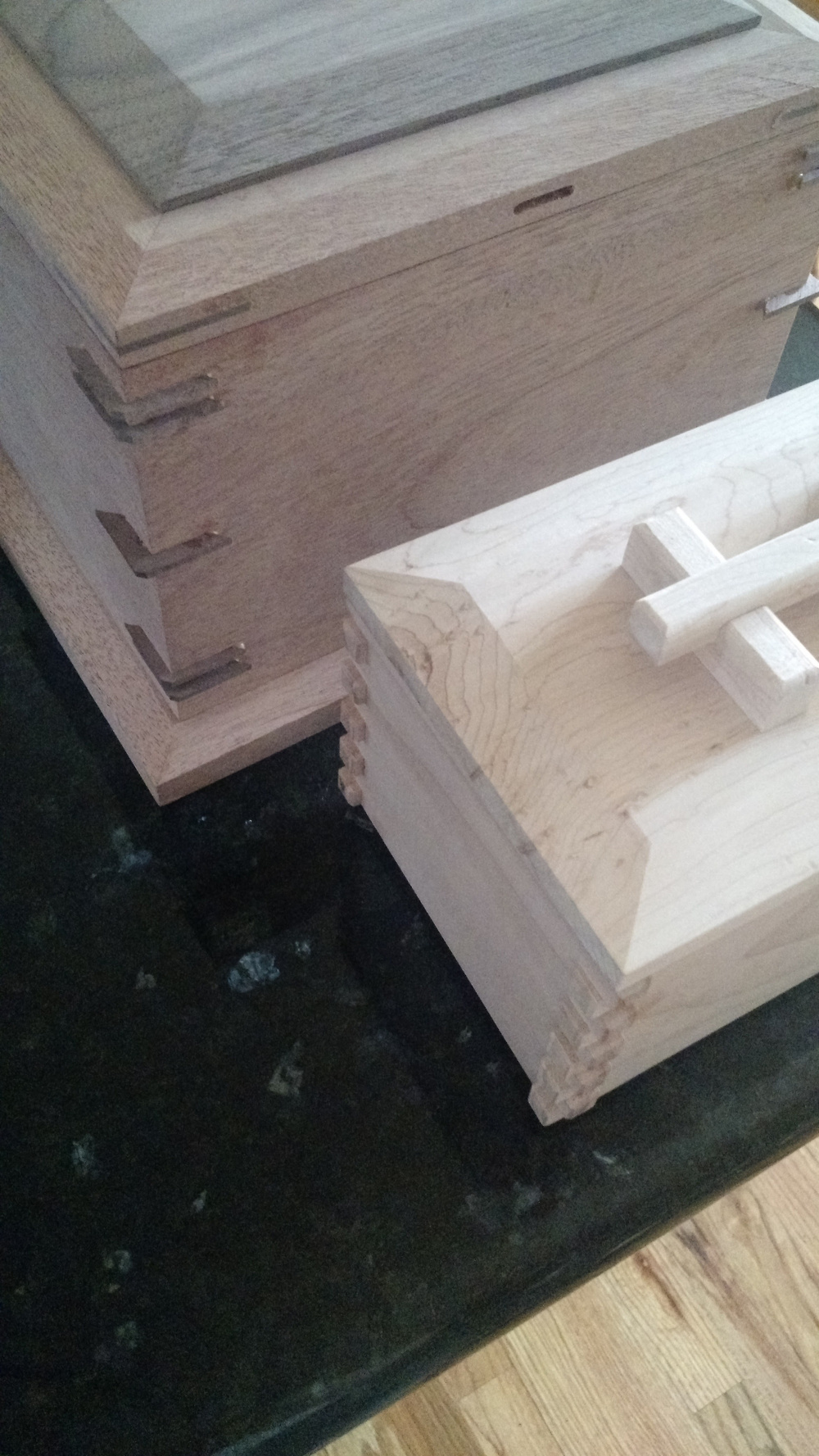 Two wooden boxes, one larger and darker and the other smaller and lighter, are placed on a dark surface.