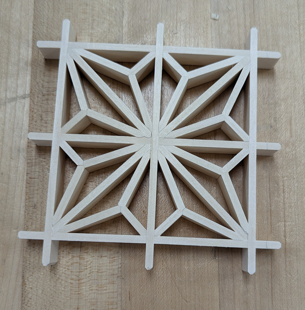 A geometric wooden lattice design featuring a symmetrical star pattern is set against a wooden surface.