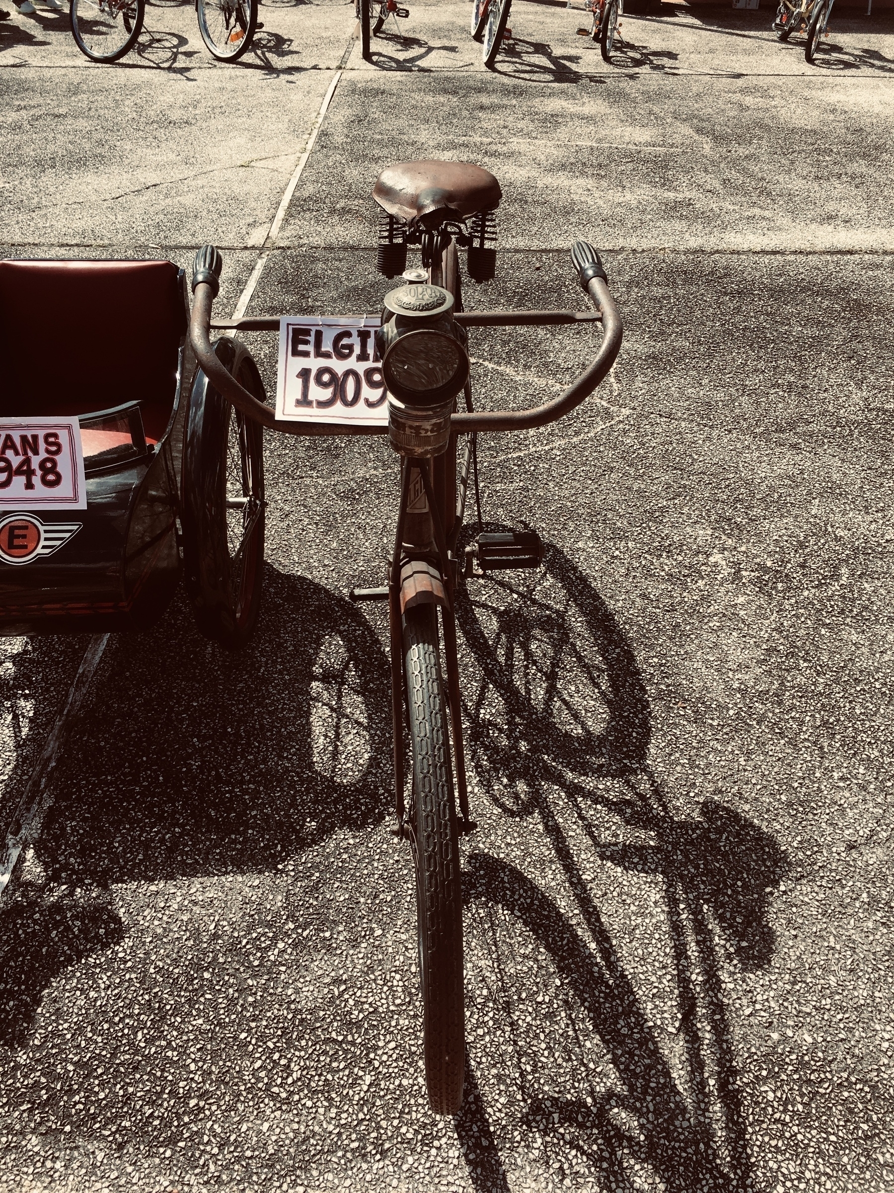 An old bike with a handwritten label “Elgin 1909” next to a small wagon