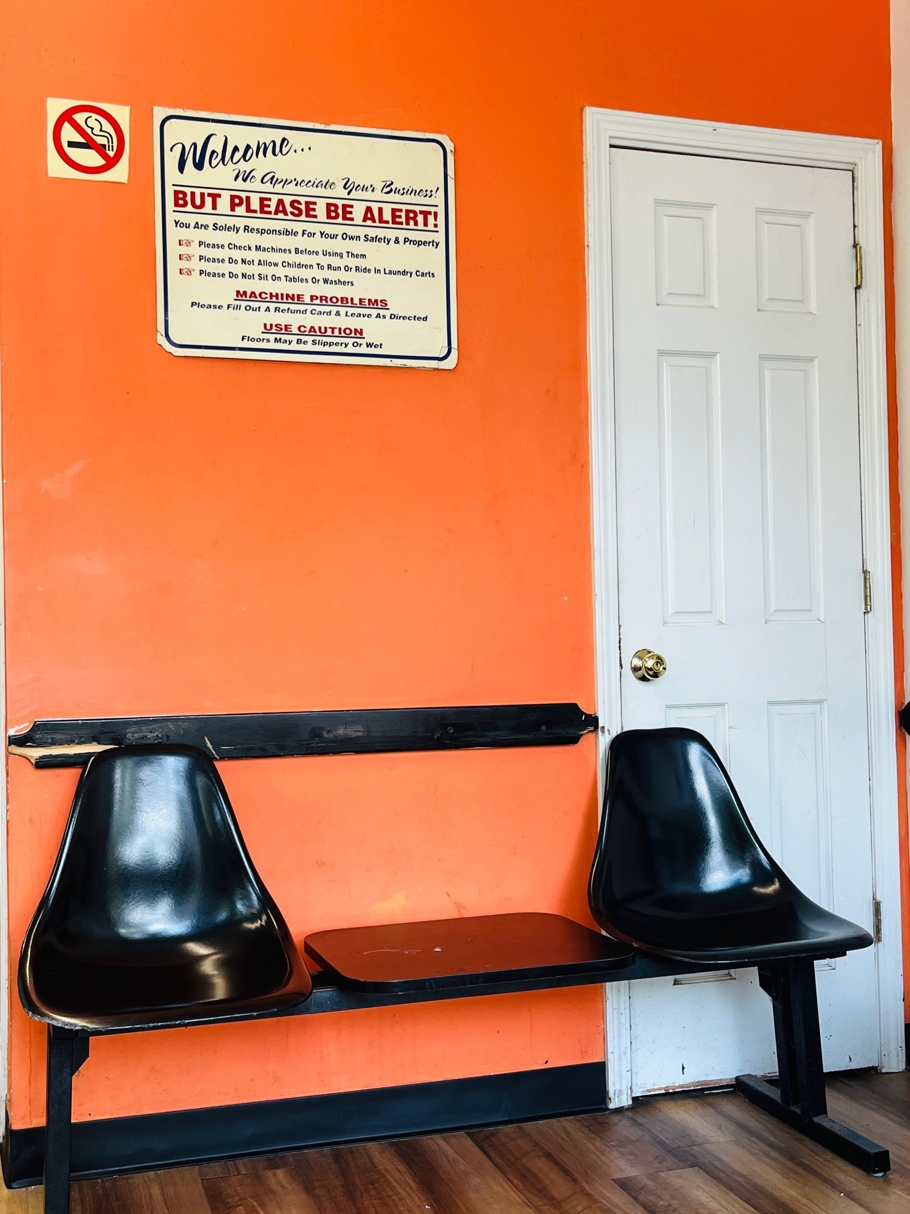 Two black chairs against an orange wall with a vintage sign above