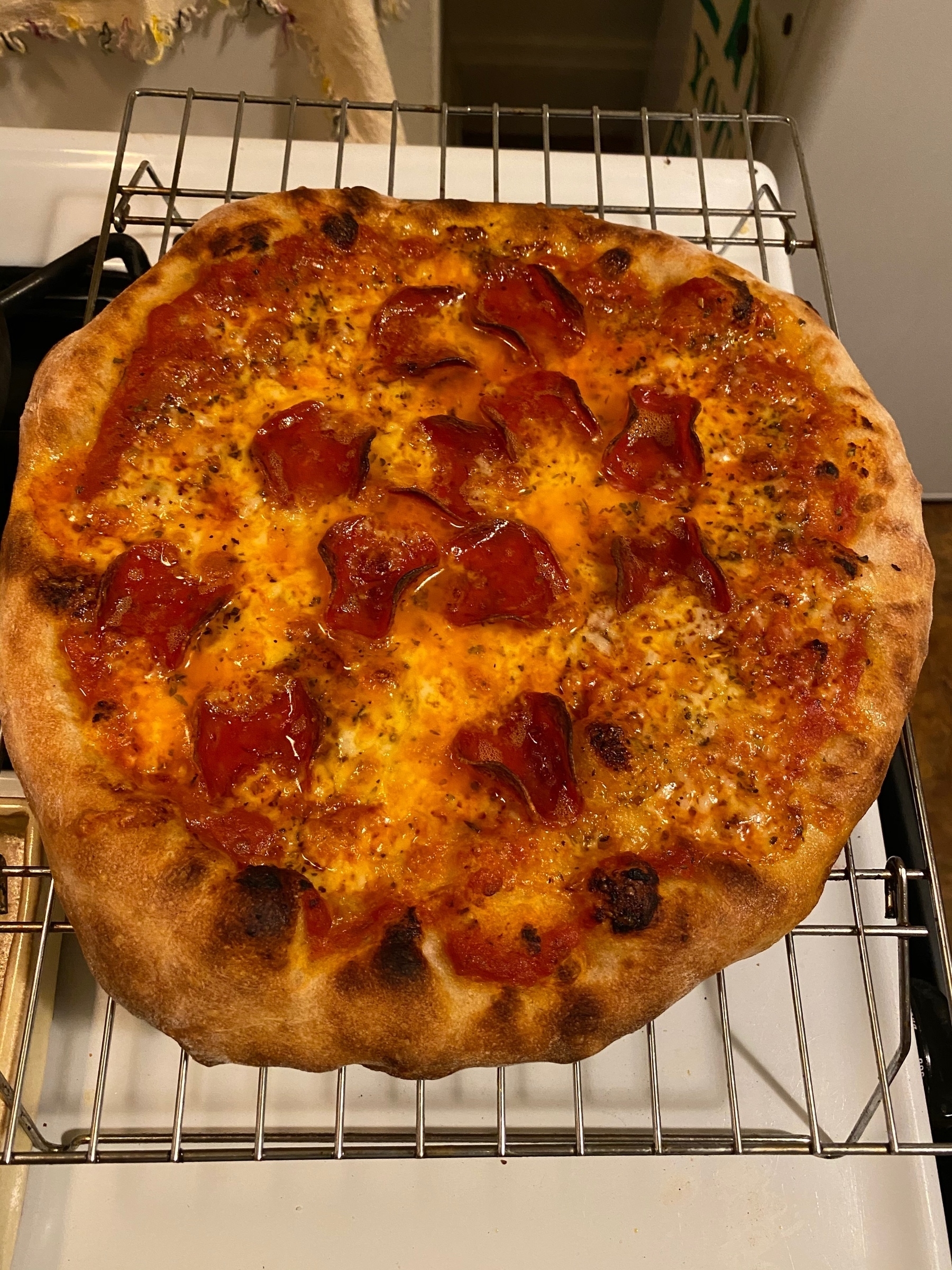 A small pepperoni pizza on a cooling rack.