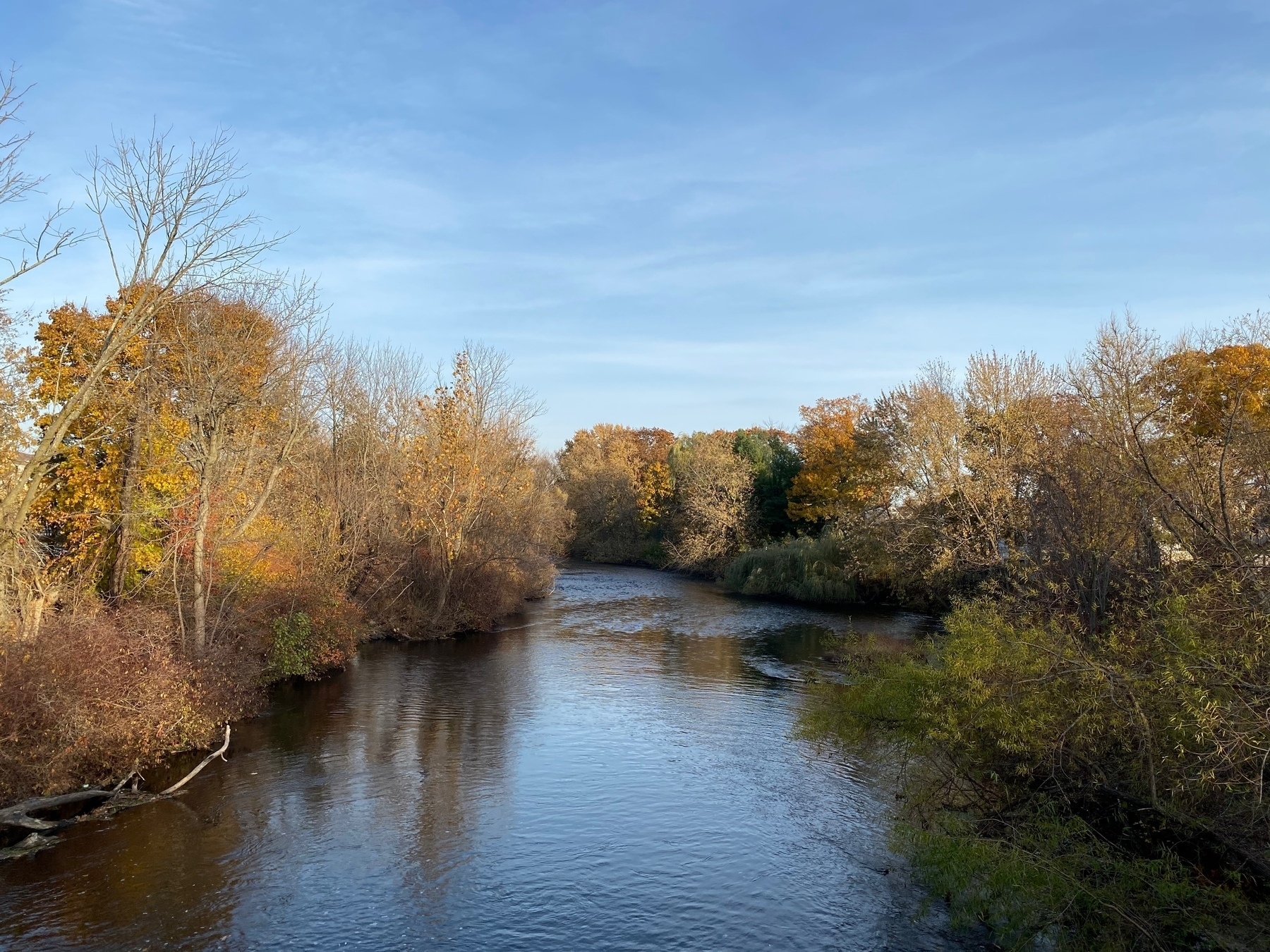 View of a river with trees in fading fall colors along each bank.