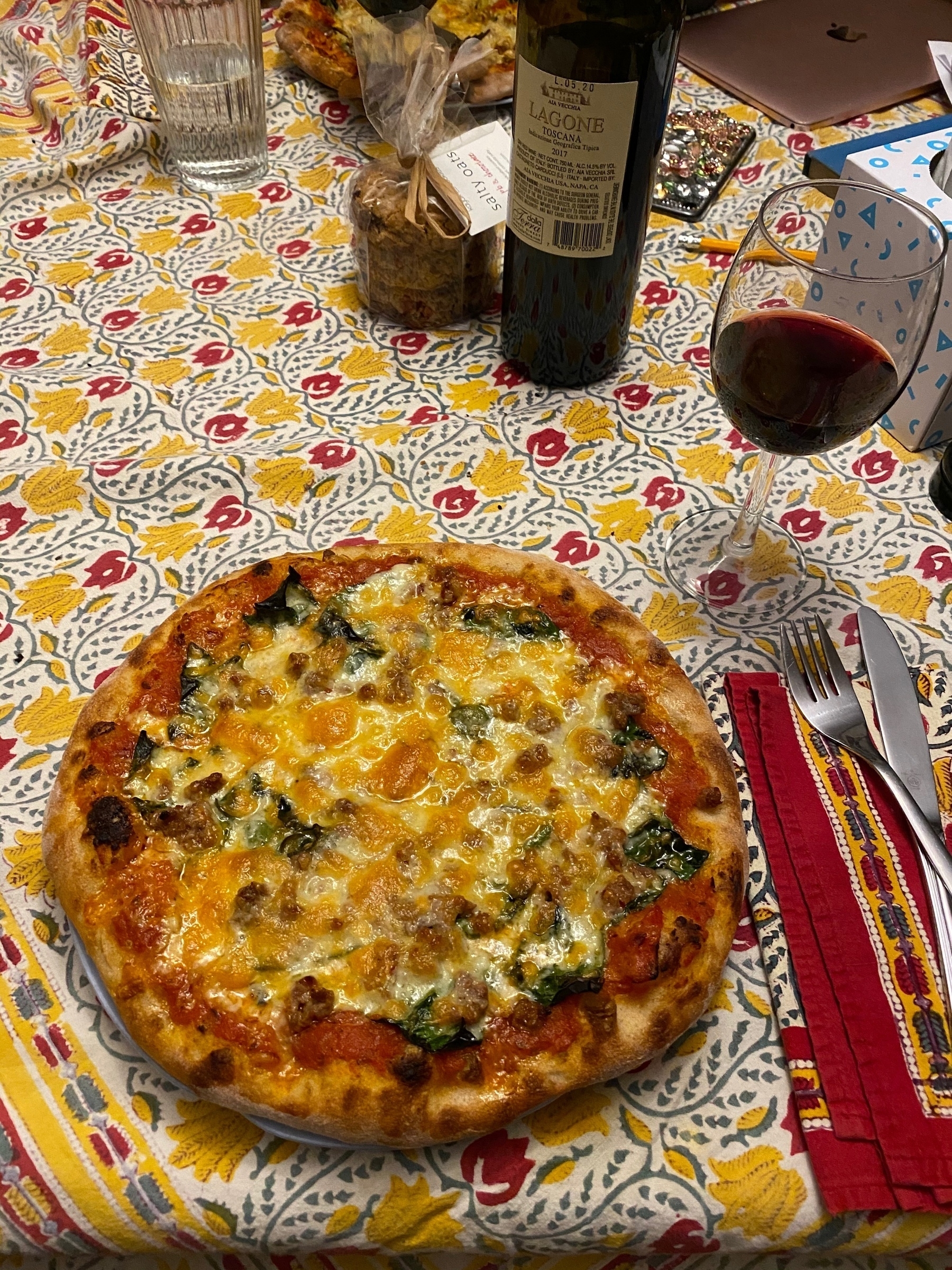 A small pizza on a table with a glass of wine and a wine bottle.