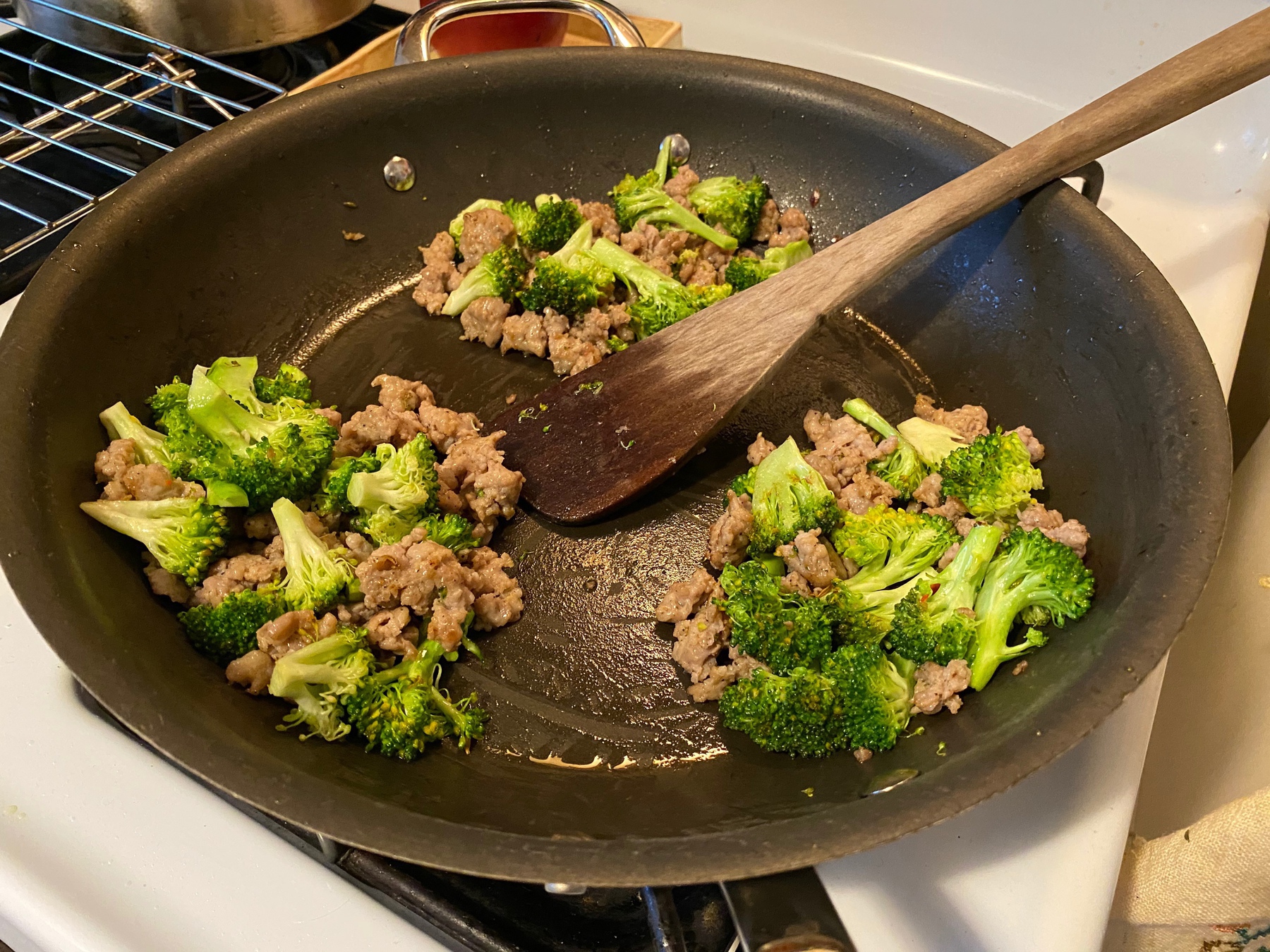 Close up of broccoli and sausage in a skillet on top of a stove.
