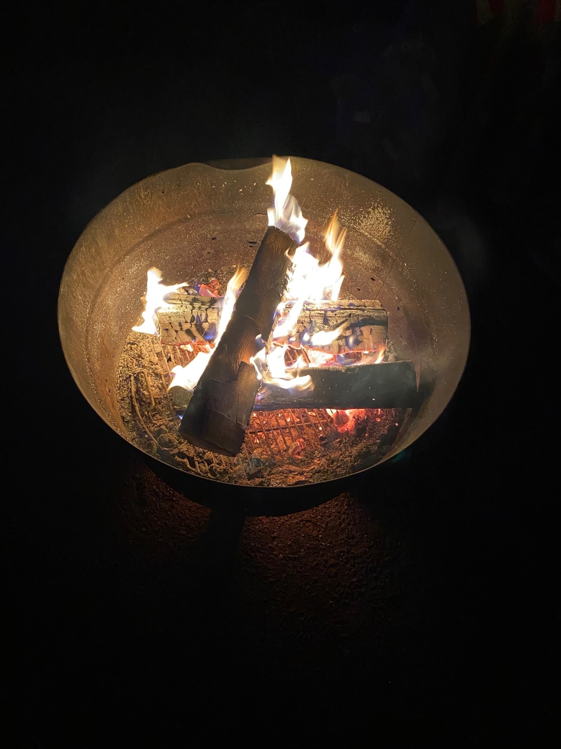 Logs burning in a large metal bucket.