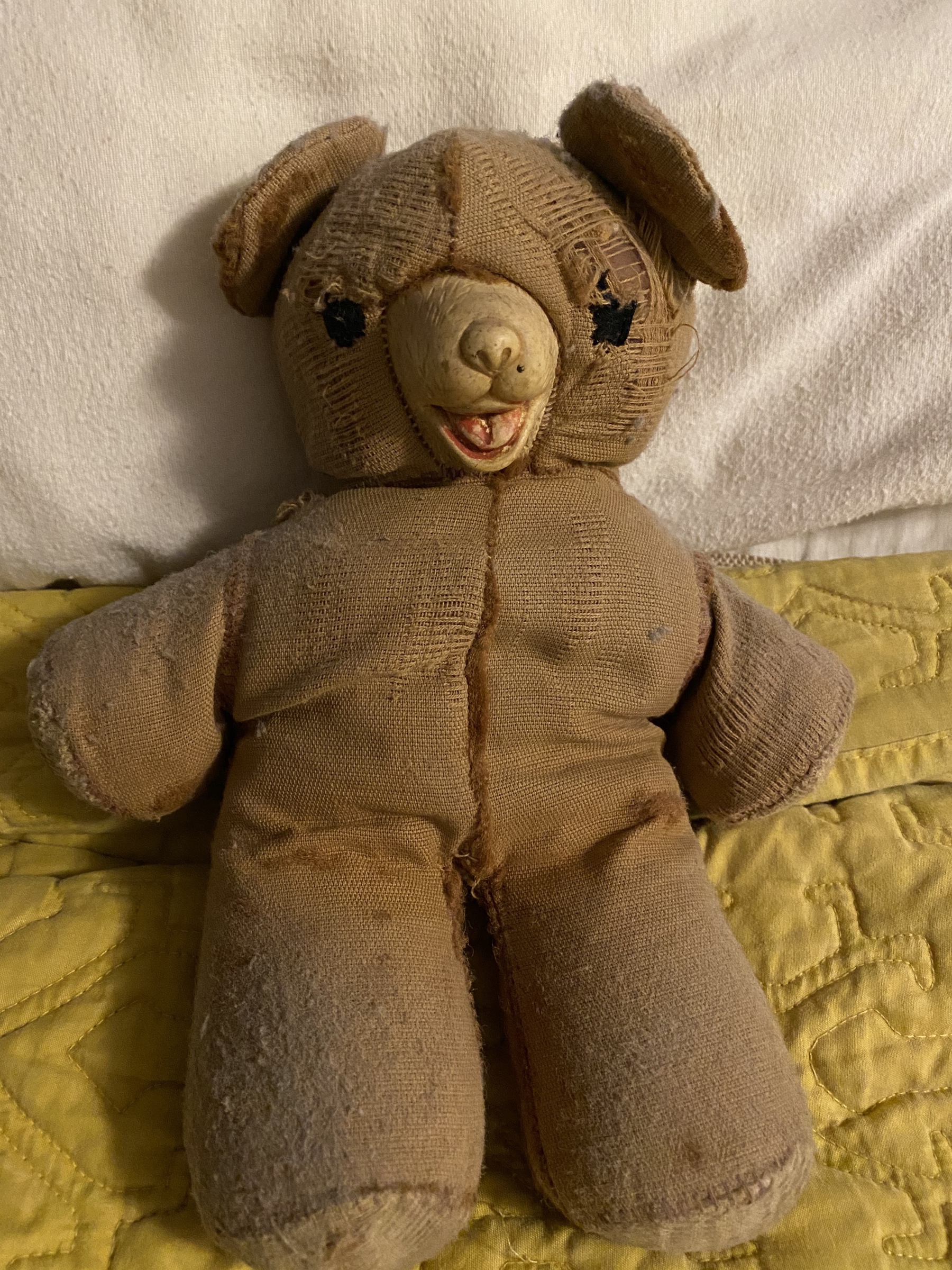 Close up of a very worn small stuffed bear.