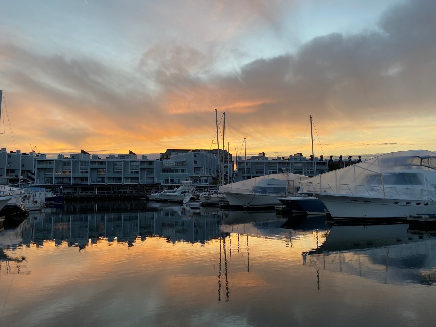 View of Charlestown Marina at sunset, the orange light shining on the clouds and reflected in the still waters below.