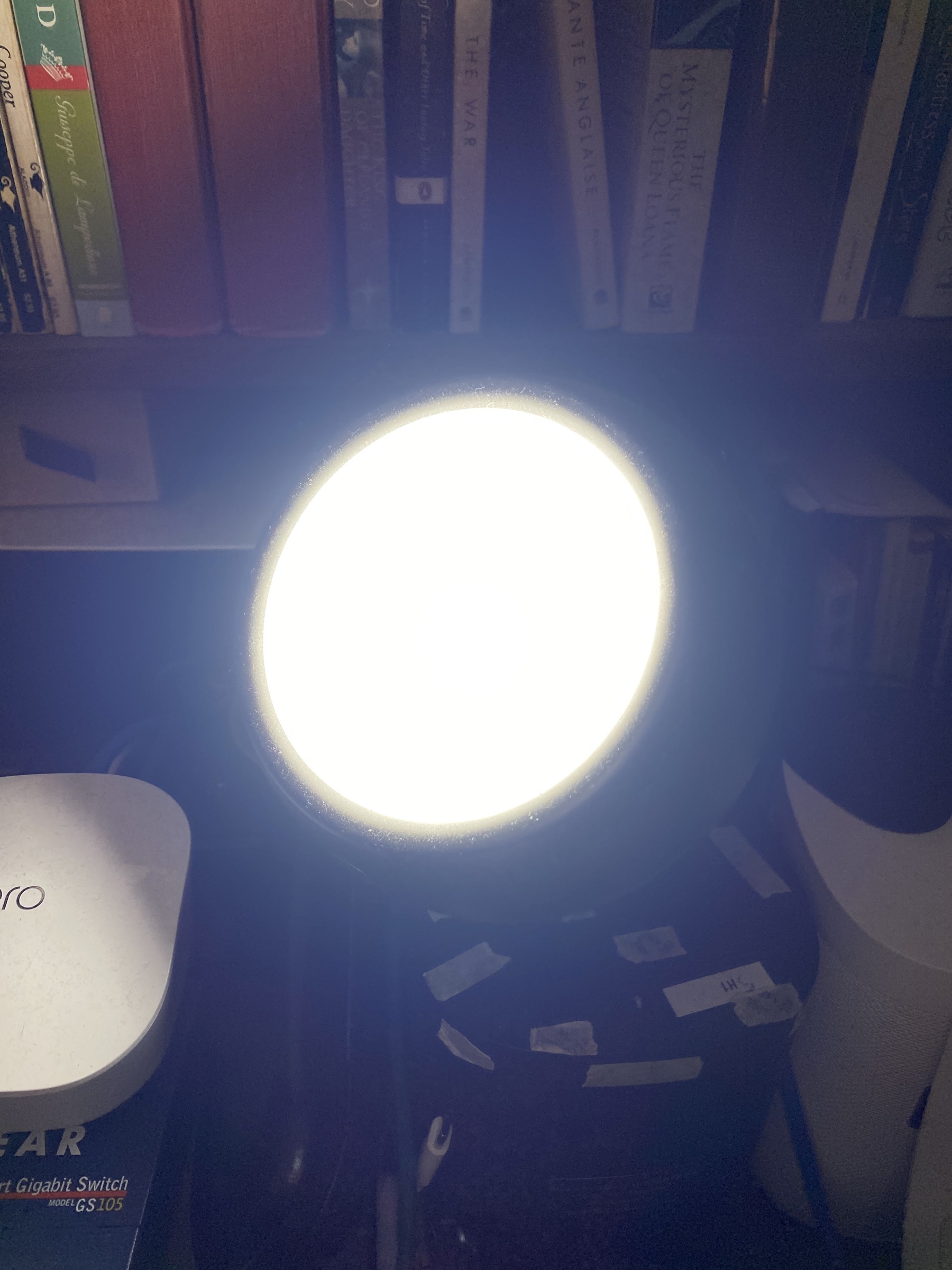 Close up of a bright light in front of a bookshelf.