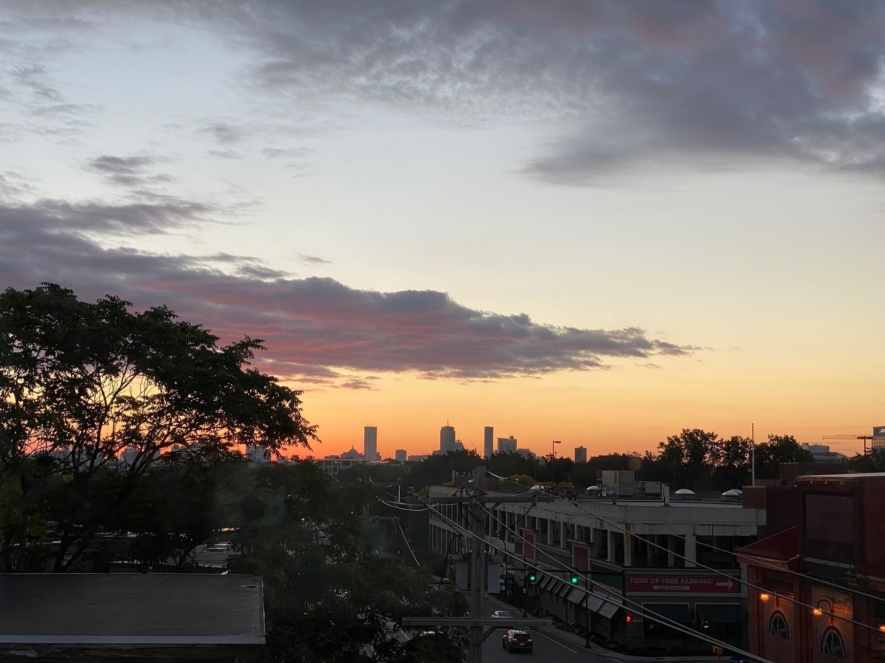 Sunset view of the Boston skyline with a dark street below.