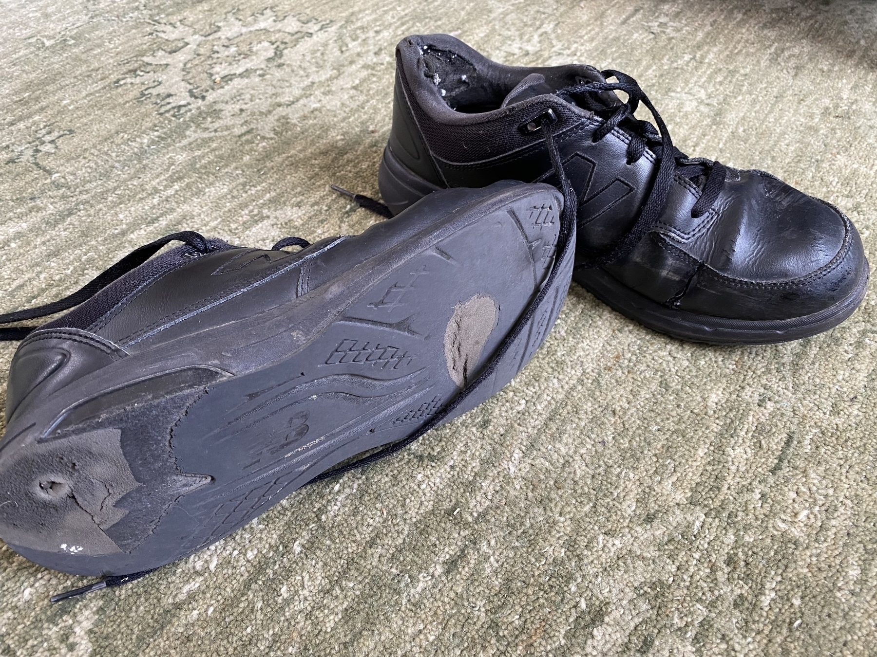 Close up of two worn black shoes.