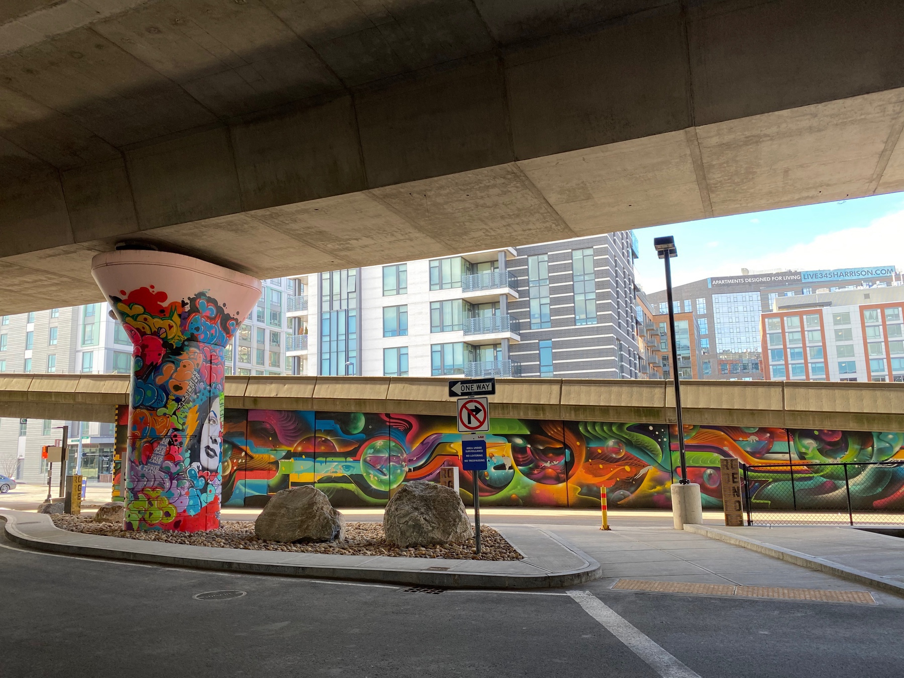 View of a colorful abstract mural under a highway overpass.