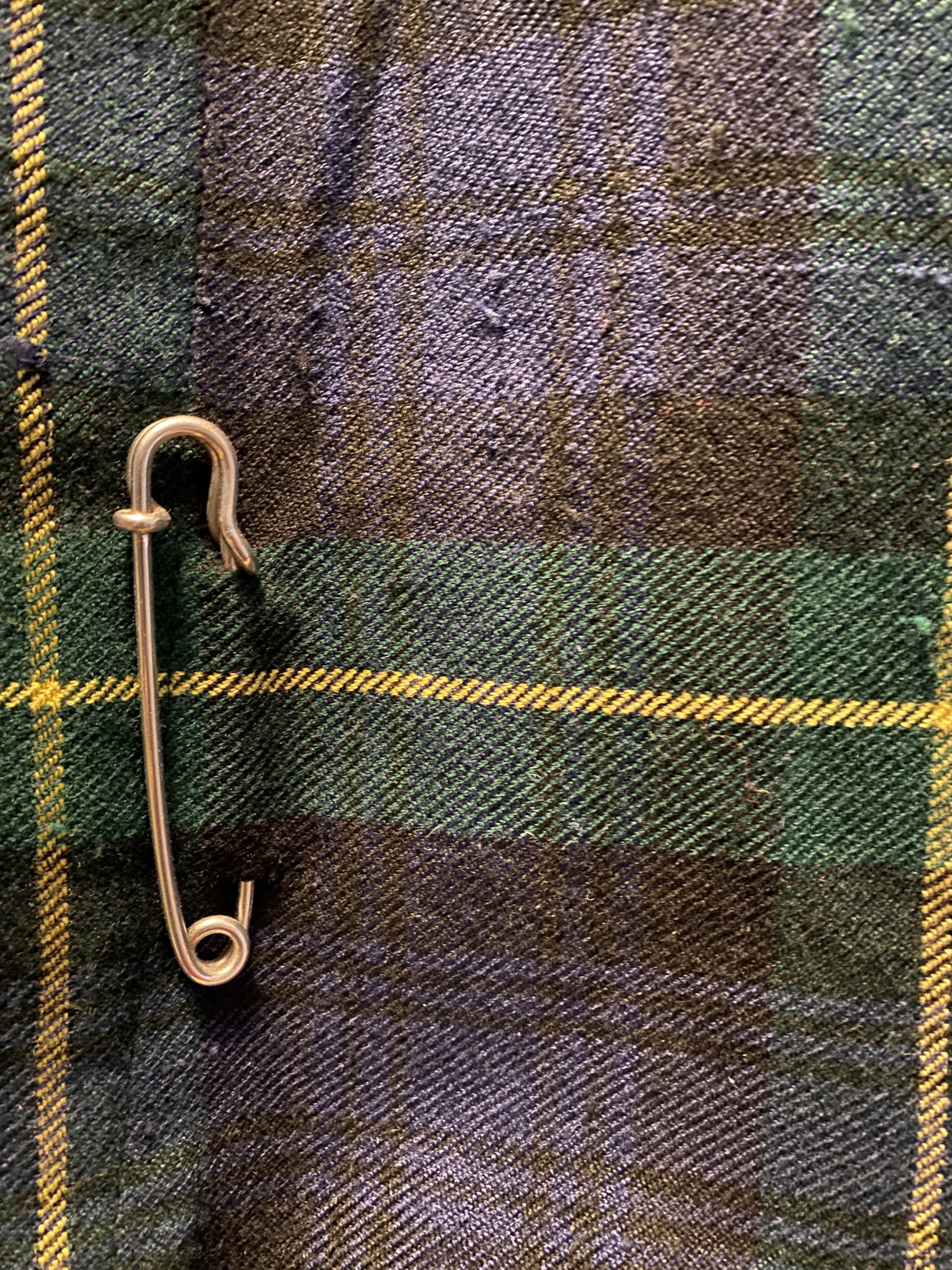 Close up of a kilt pin attached to a bit of tartan cloth.