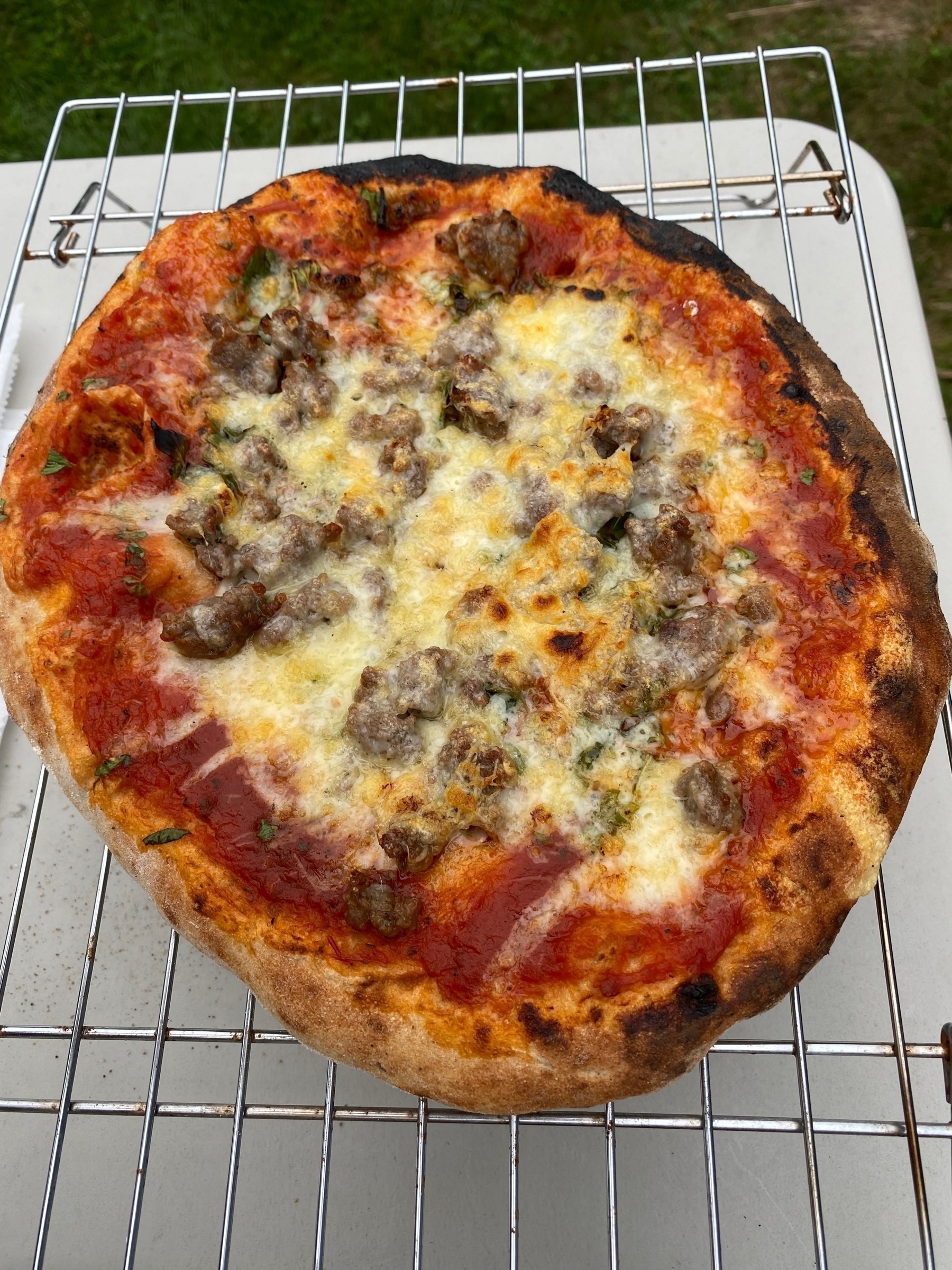 A small pizza on a cooling rack.