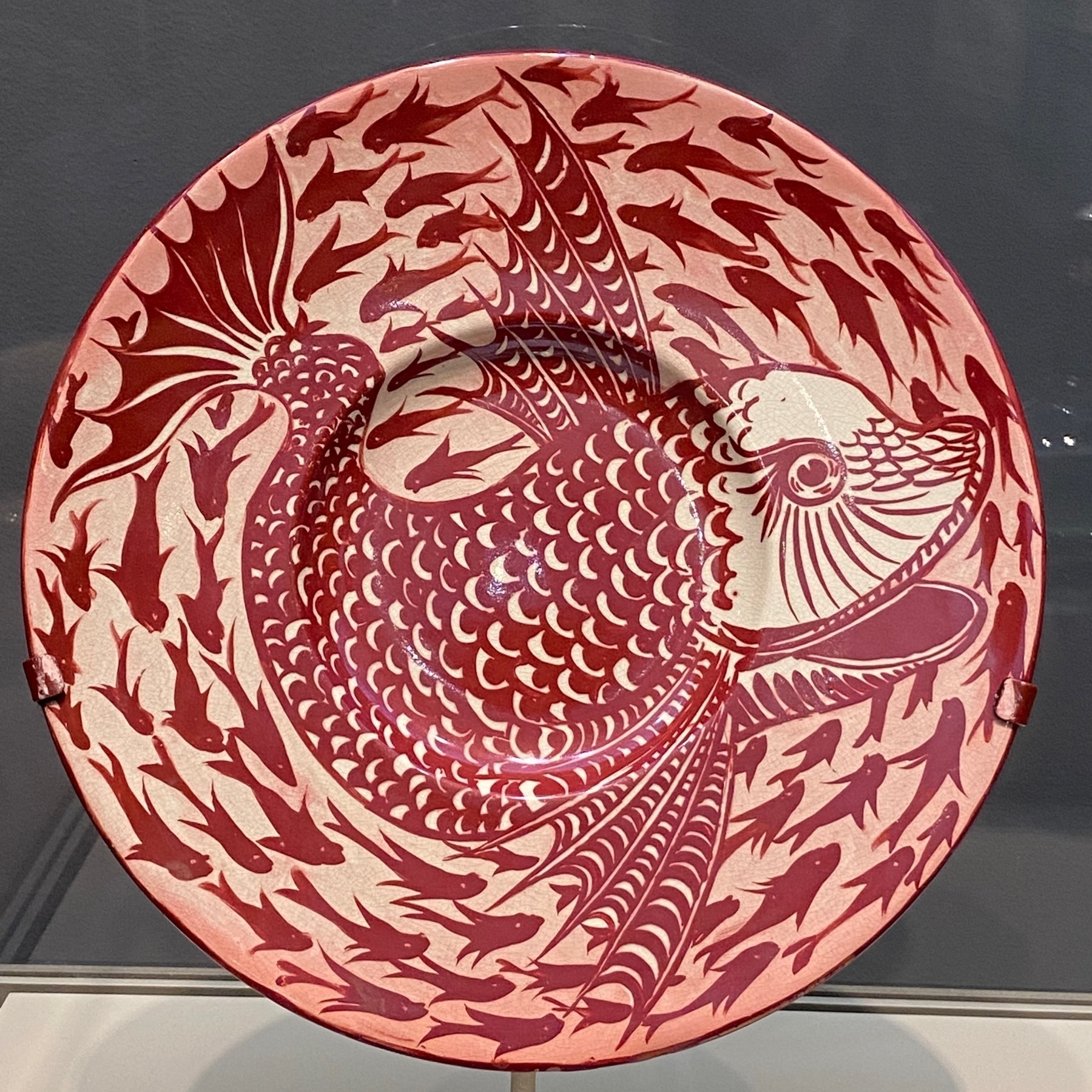 Large pinkish platter with a large fish in the center, surrounded by the silhouttes of small fish around the edge.