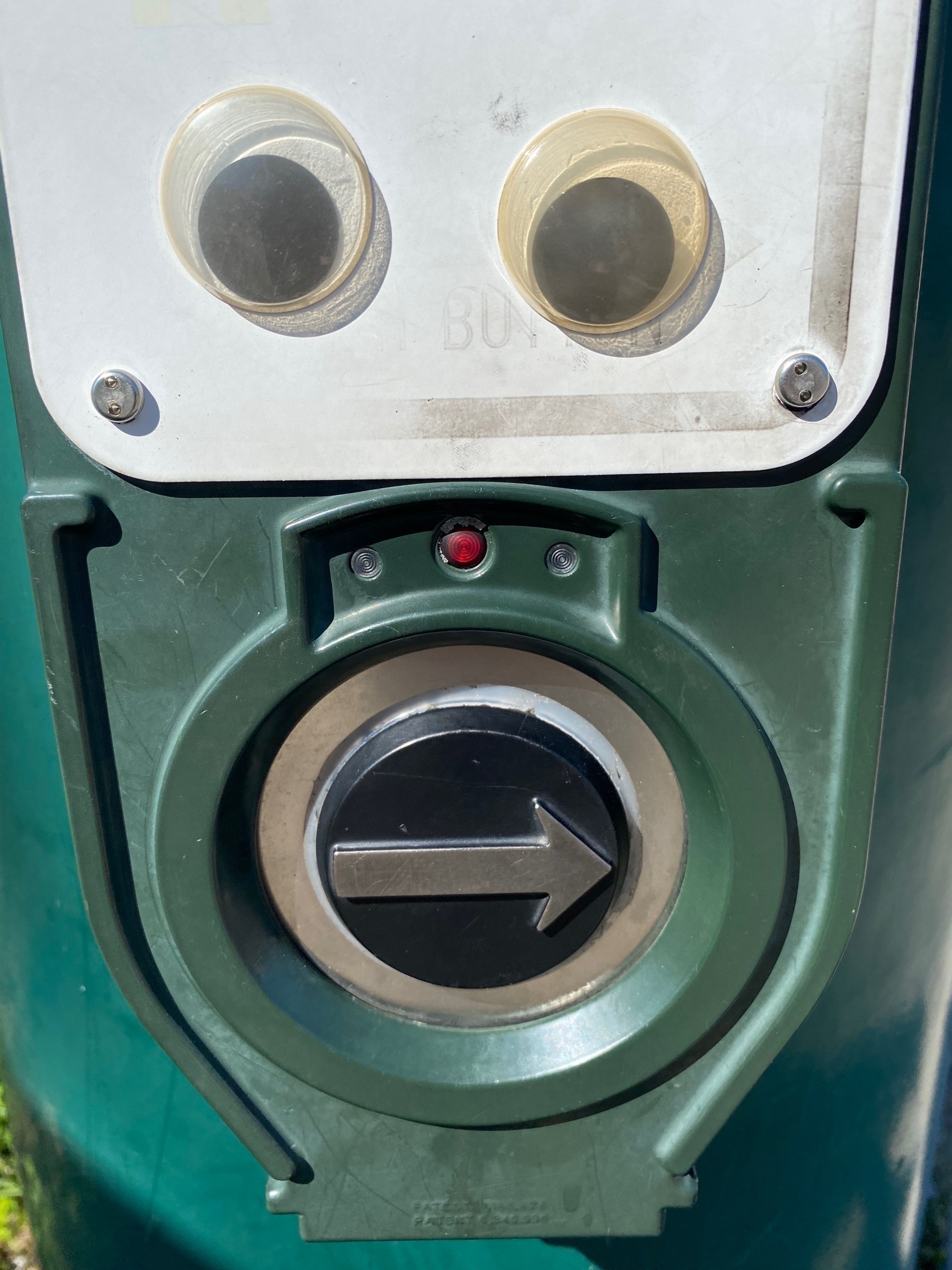 Close up view of a pedestrian crossing button with googly eyes above.