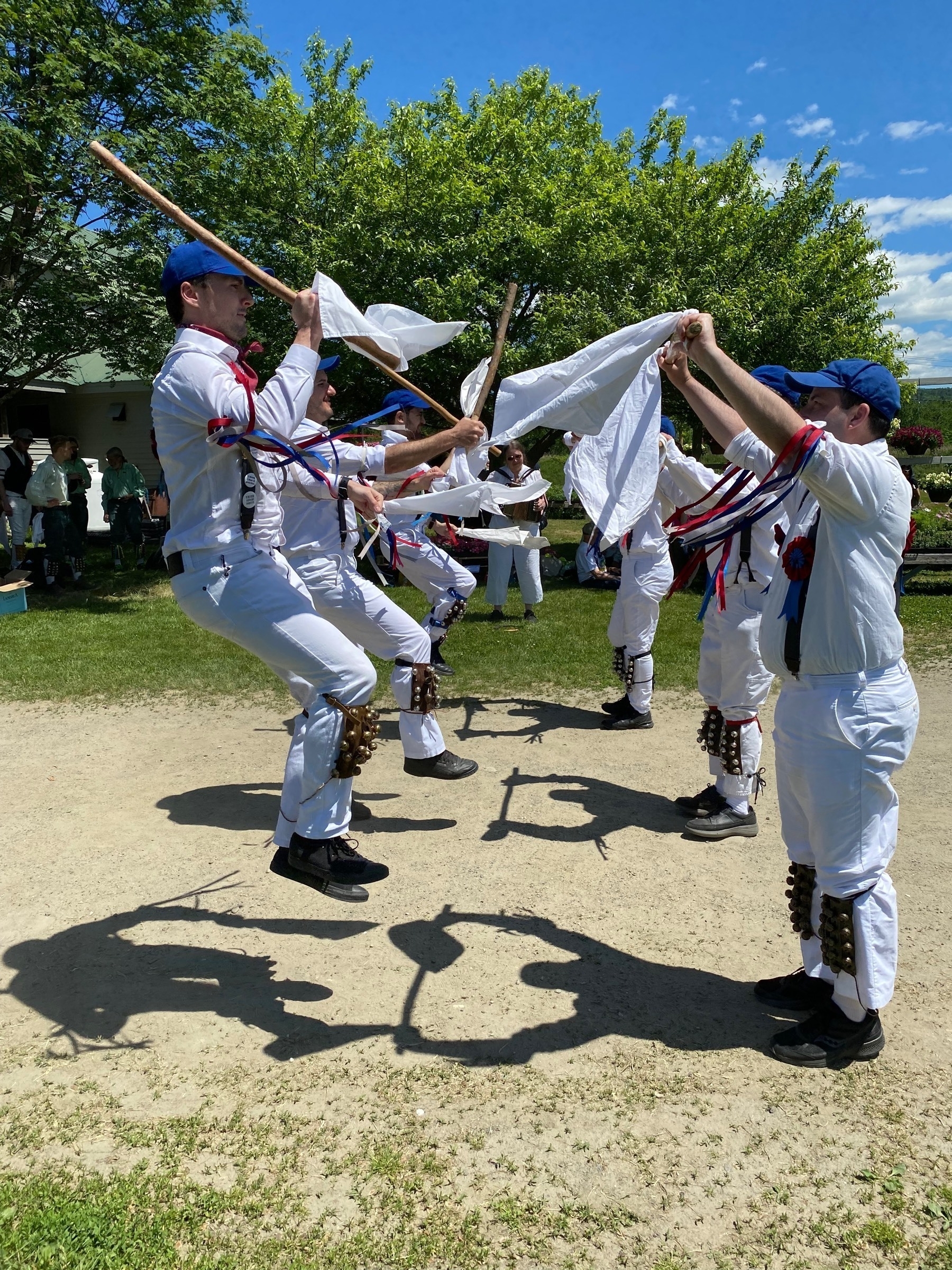 Morris dancers, one side leaping into the air to clash sticks being presented by the other side.