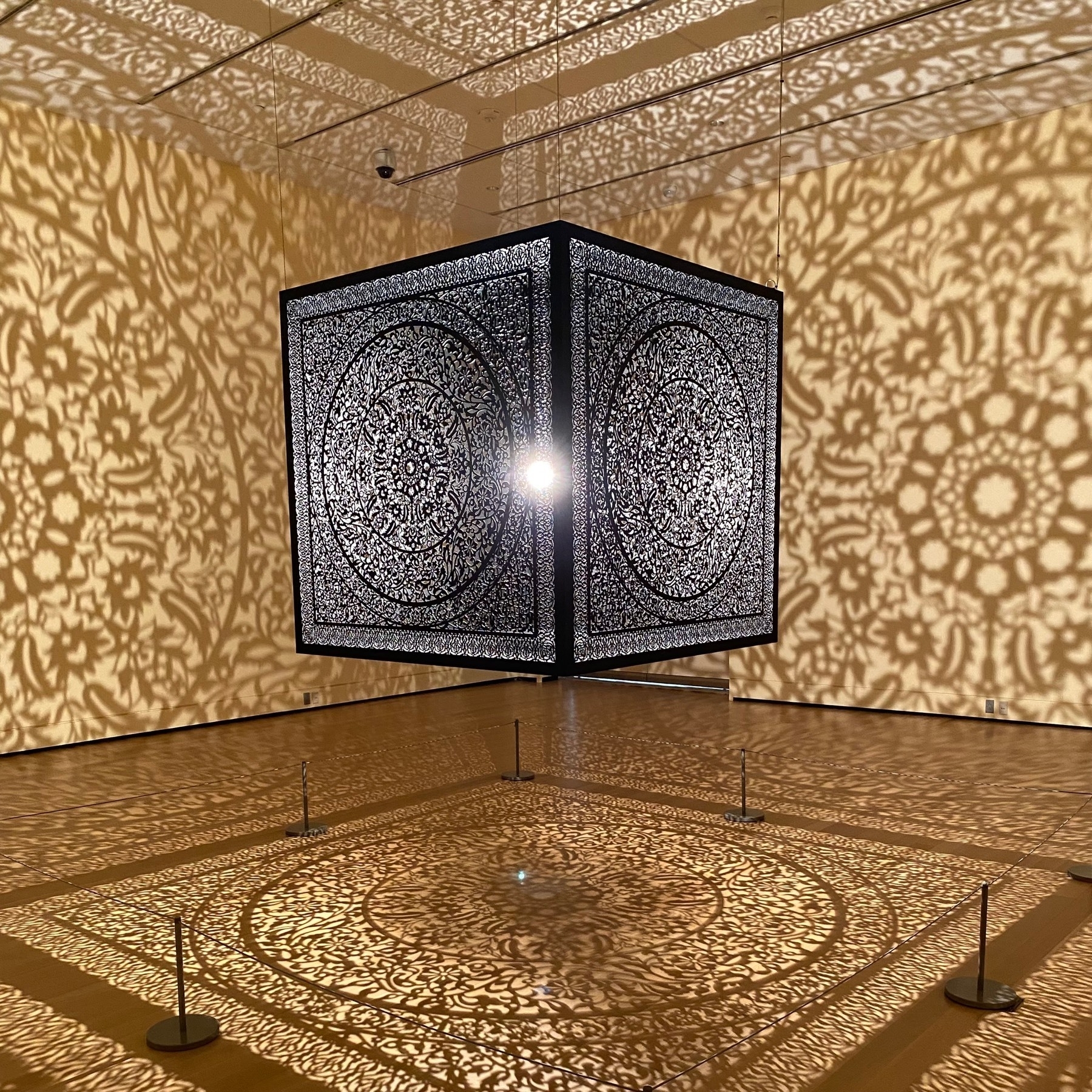Anila Quayyum Agha, All the Flowers Are for Me,
2015, metal cube sculpture with a bright light in the center casting an elaborate mesh of shadows on the walls, ceiling, and floor.