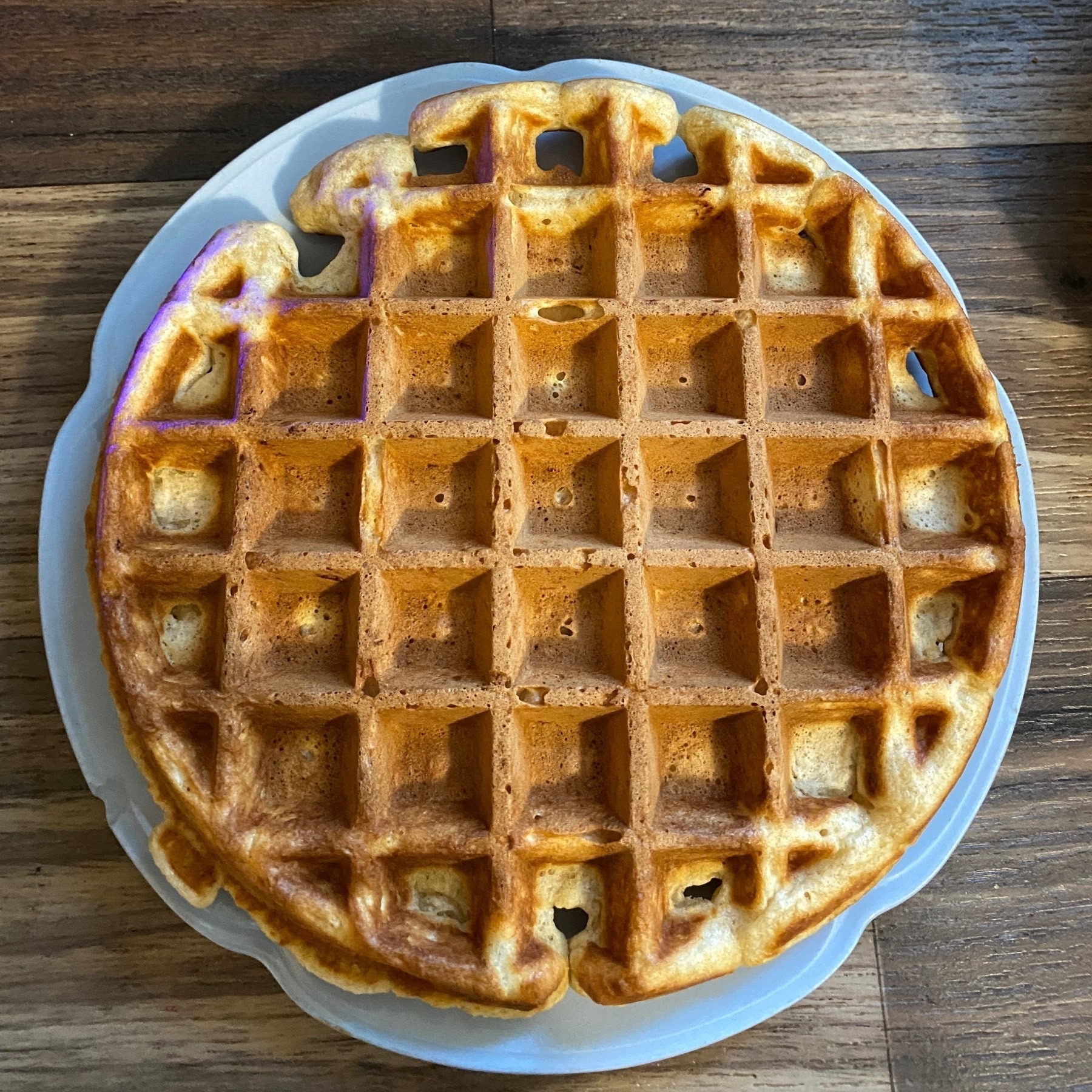 A round waffle sitting on a blue plate.