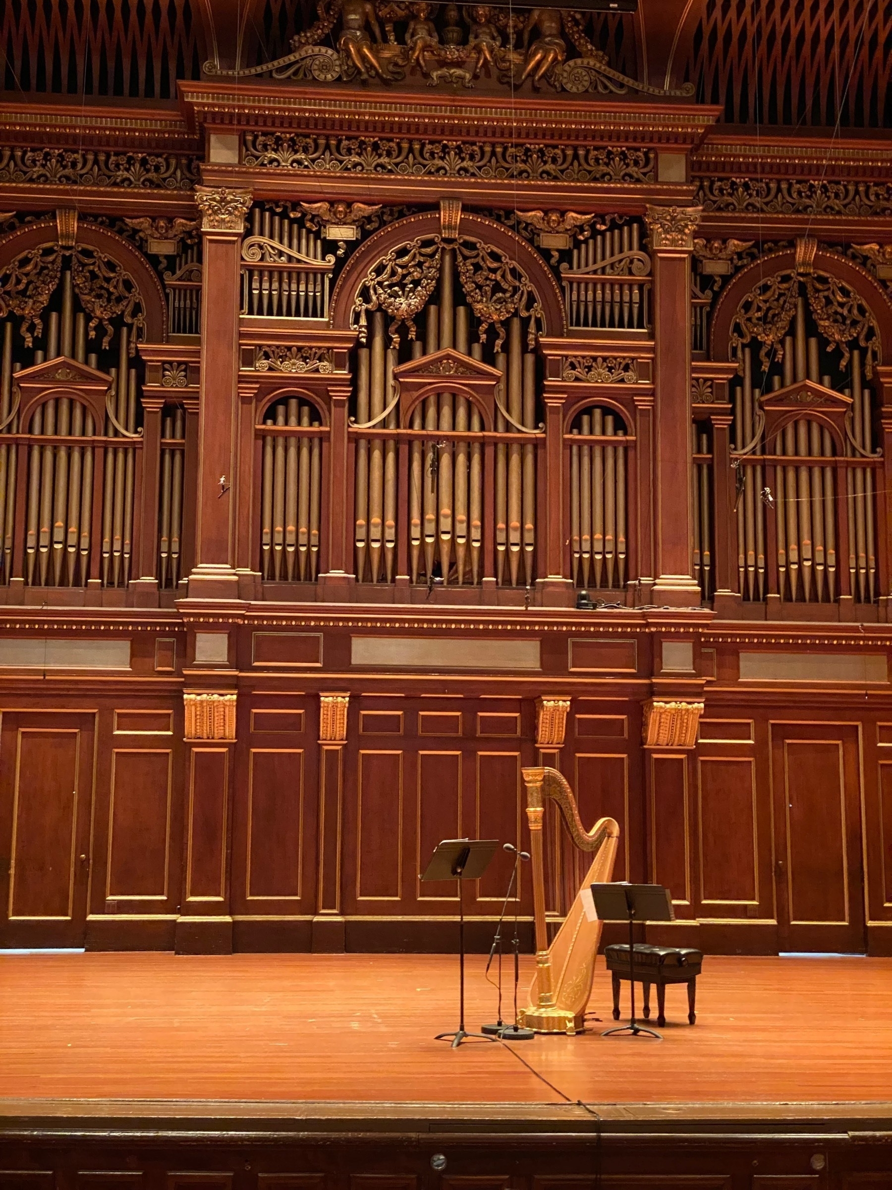 Stage with a large harp and music stands, a large pipe organ built into the rear wall.