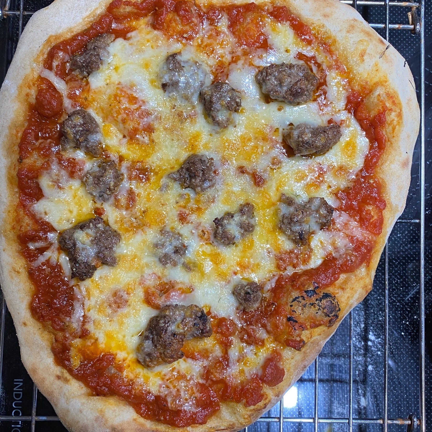 A small pizza on a cooling rack.