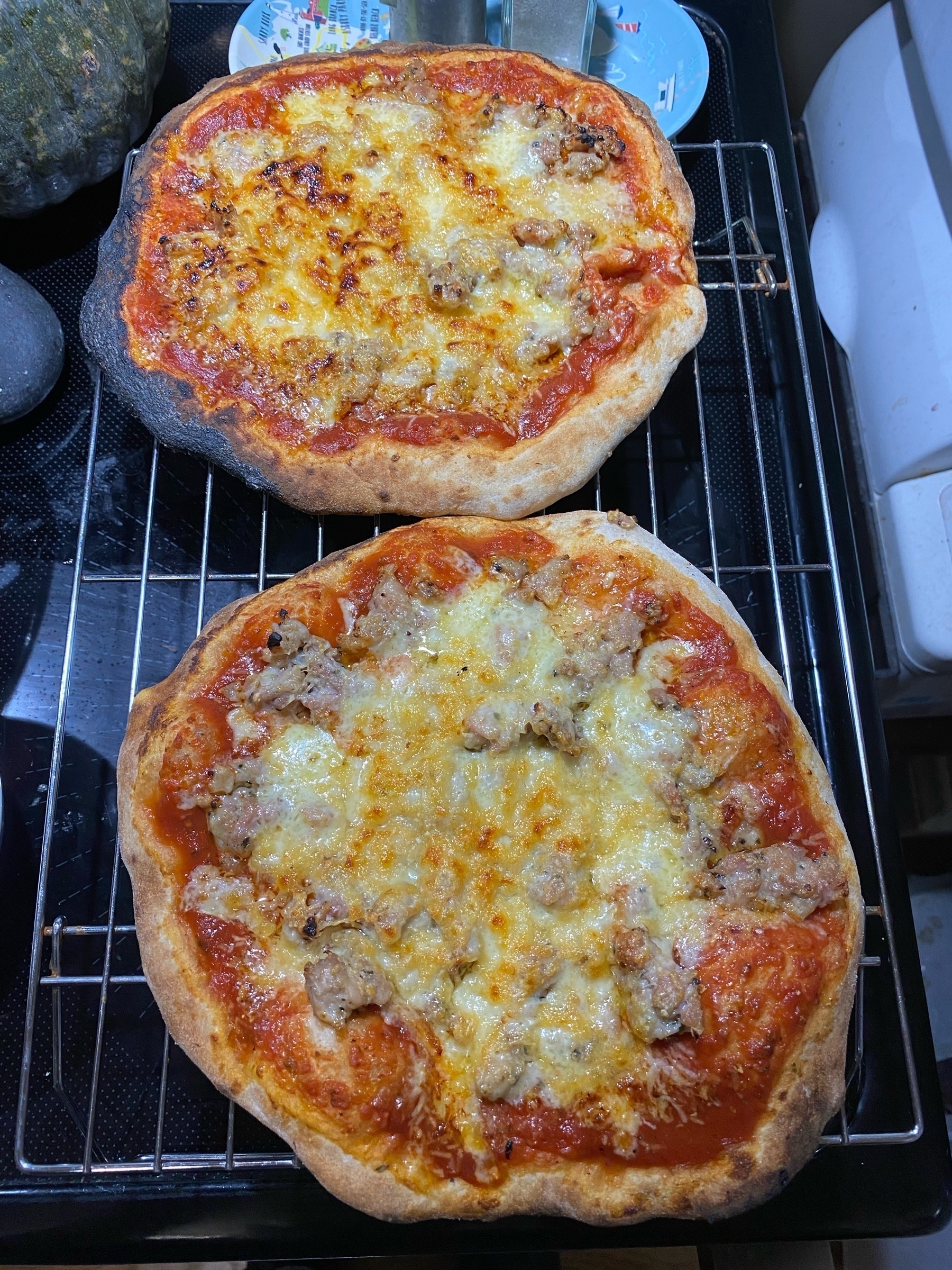 Two small pizzas on a cooling rack.