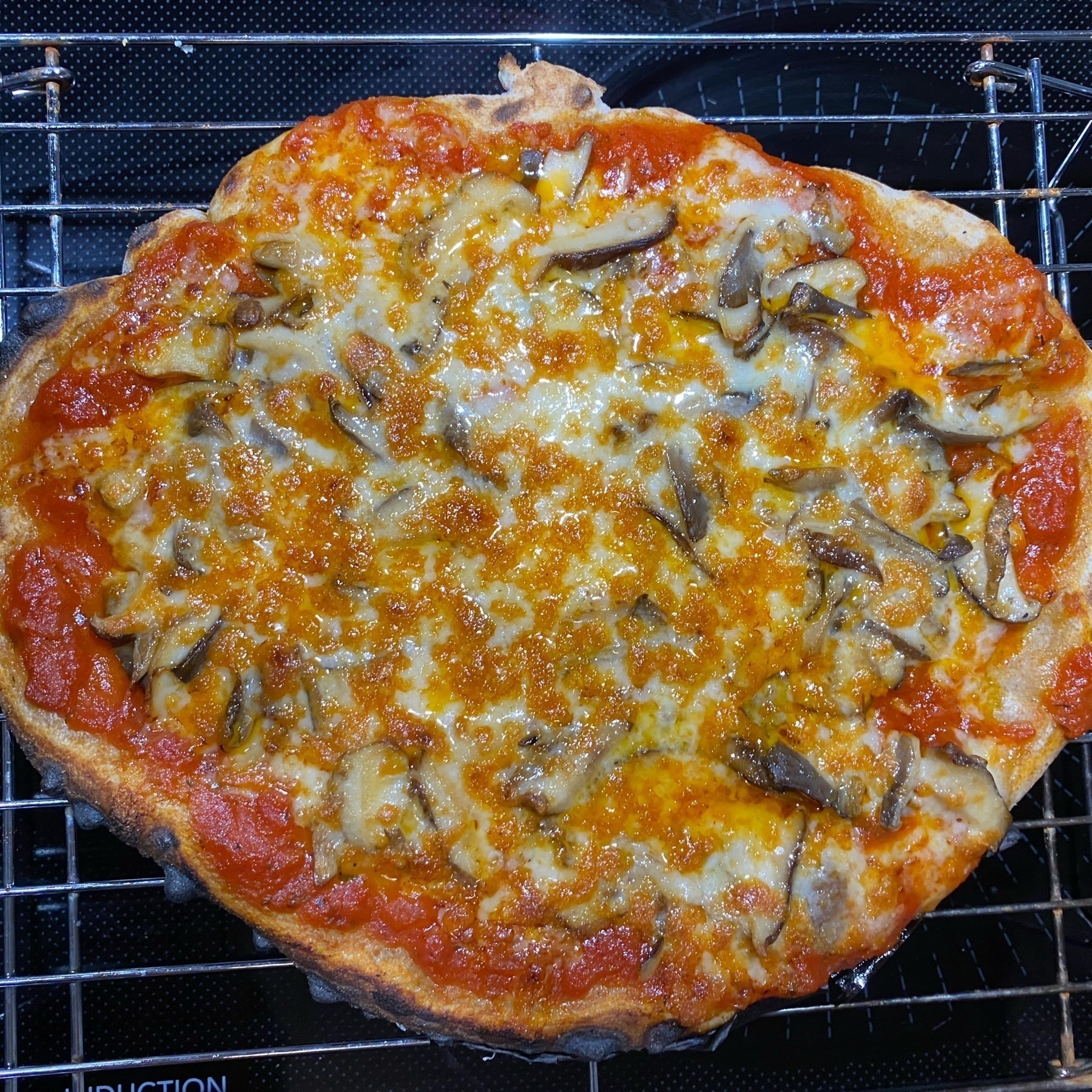 Small mushroom pizza on a cooling rack.