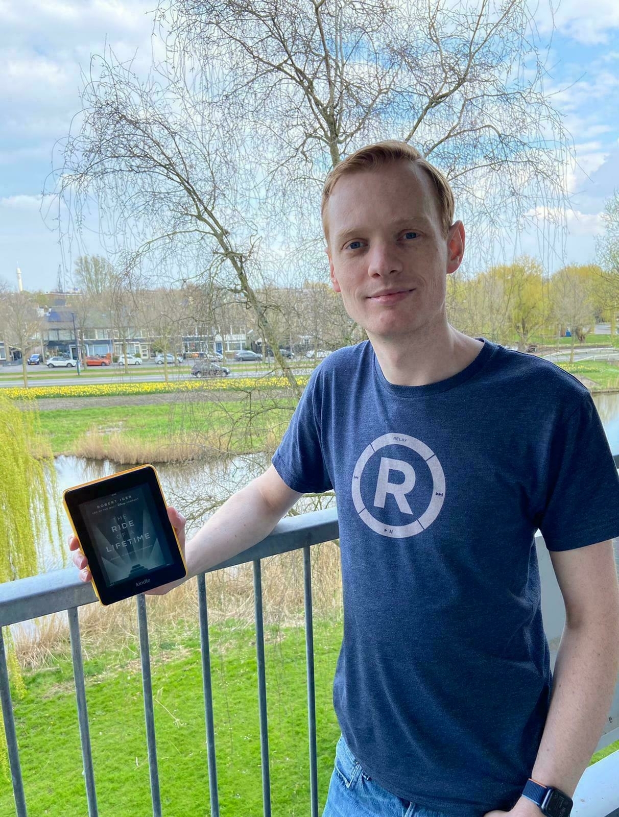 Photo of me holding a kindle with the cover of the book Ride of a Lifetime