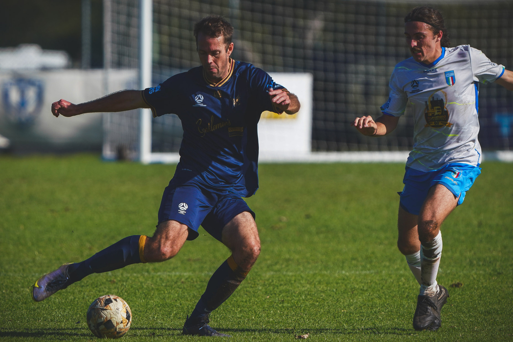 Two soccer players in action during a match on a grassy field.