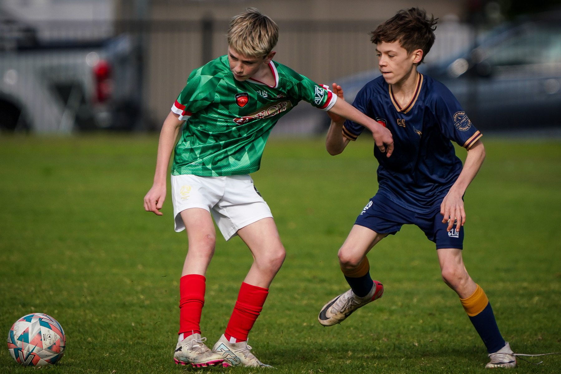 Two young soccer players compete for the ball on a grassy field.