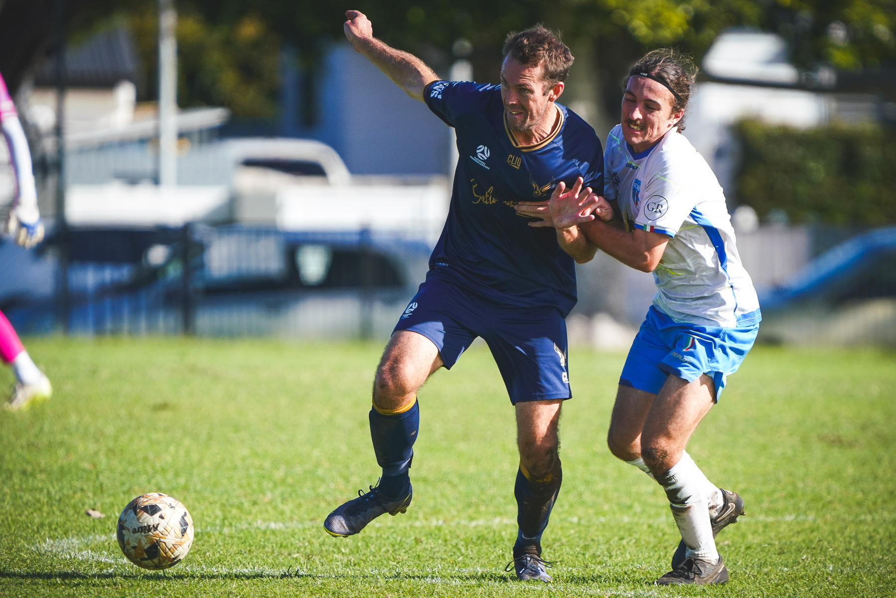 Two soccer players are competing for the ball on a grassy field during a match.