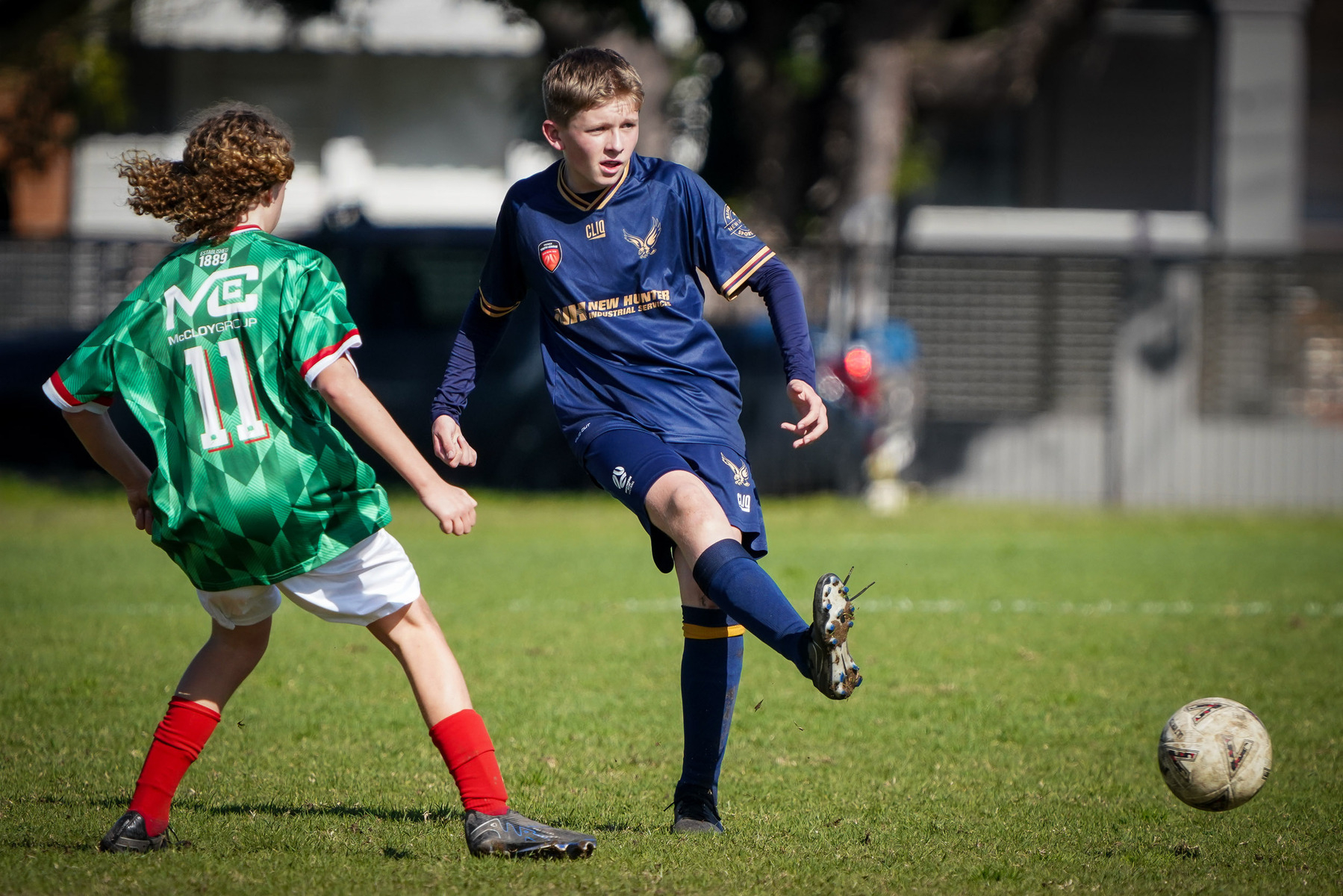 Two young soccer players are competing for the ball on a grassy field.