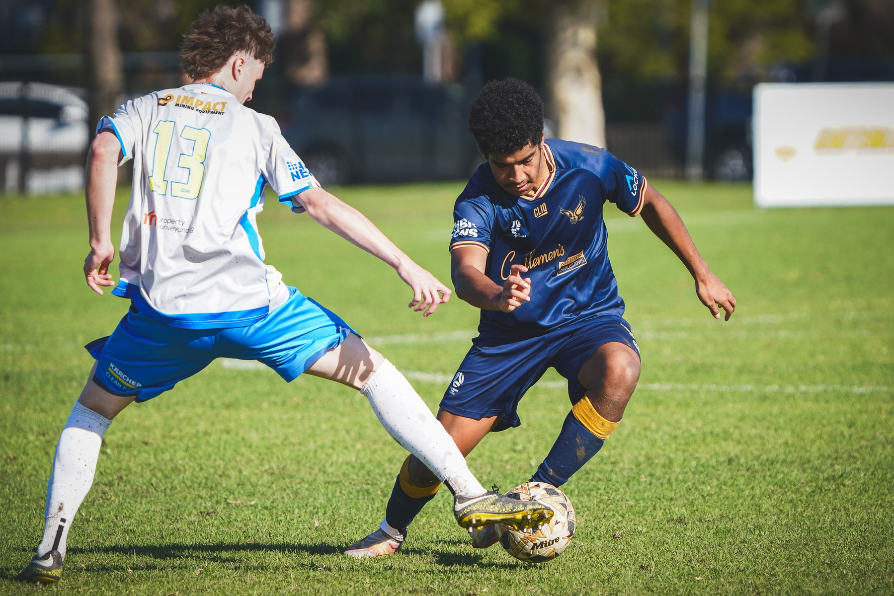 Two soccer players are competing for the ball during a match on a grassy field.