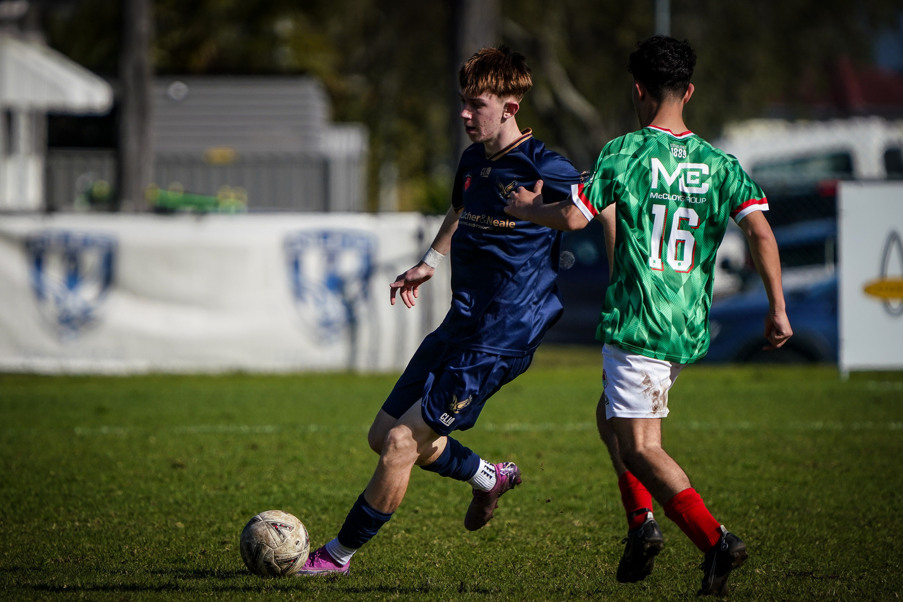 Two soccer players are actively competing for control of the ball during a match.