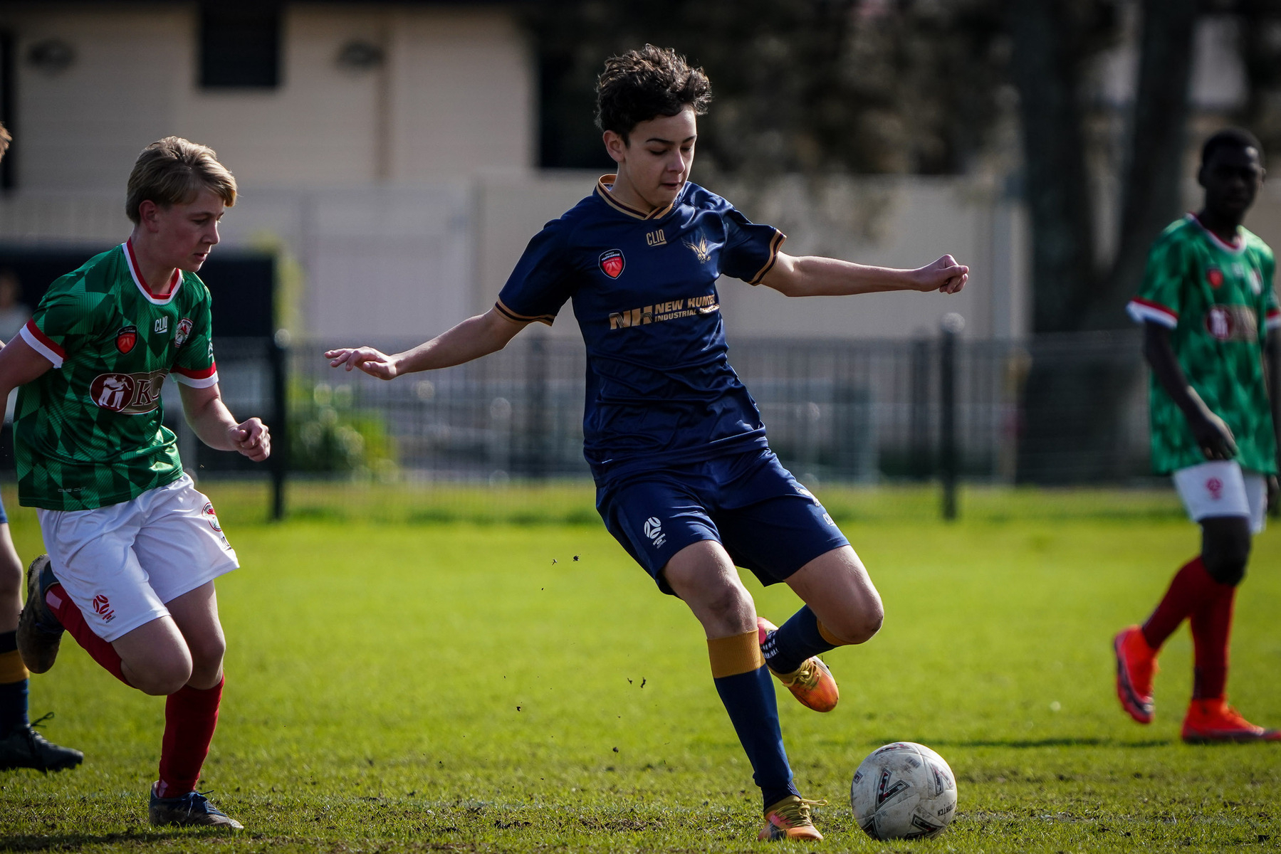 A group of young soccer players is actively engaged in a game on a grassy field, with one player in blue controlling the ball.