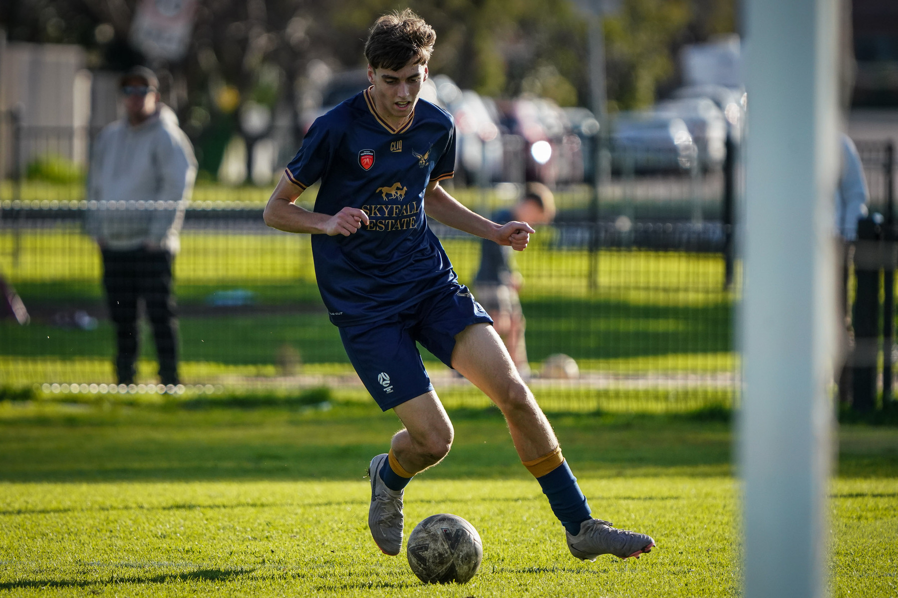 A soccer player in a blue uniform is skillfully controlling the ball on a grassy field during a game.