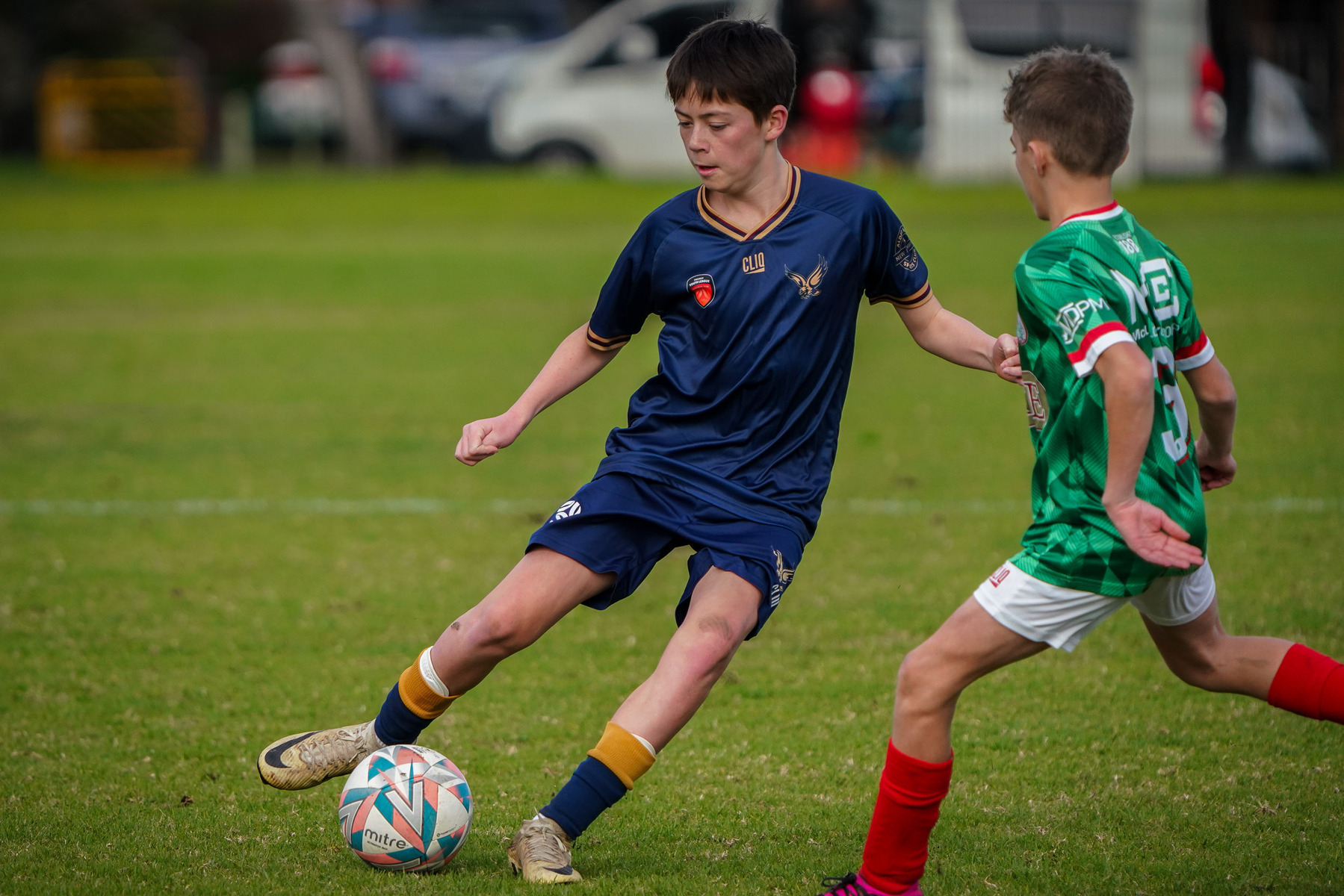 Two young soccer players compete for the ball on a grassy field.