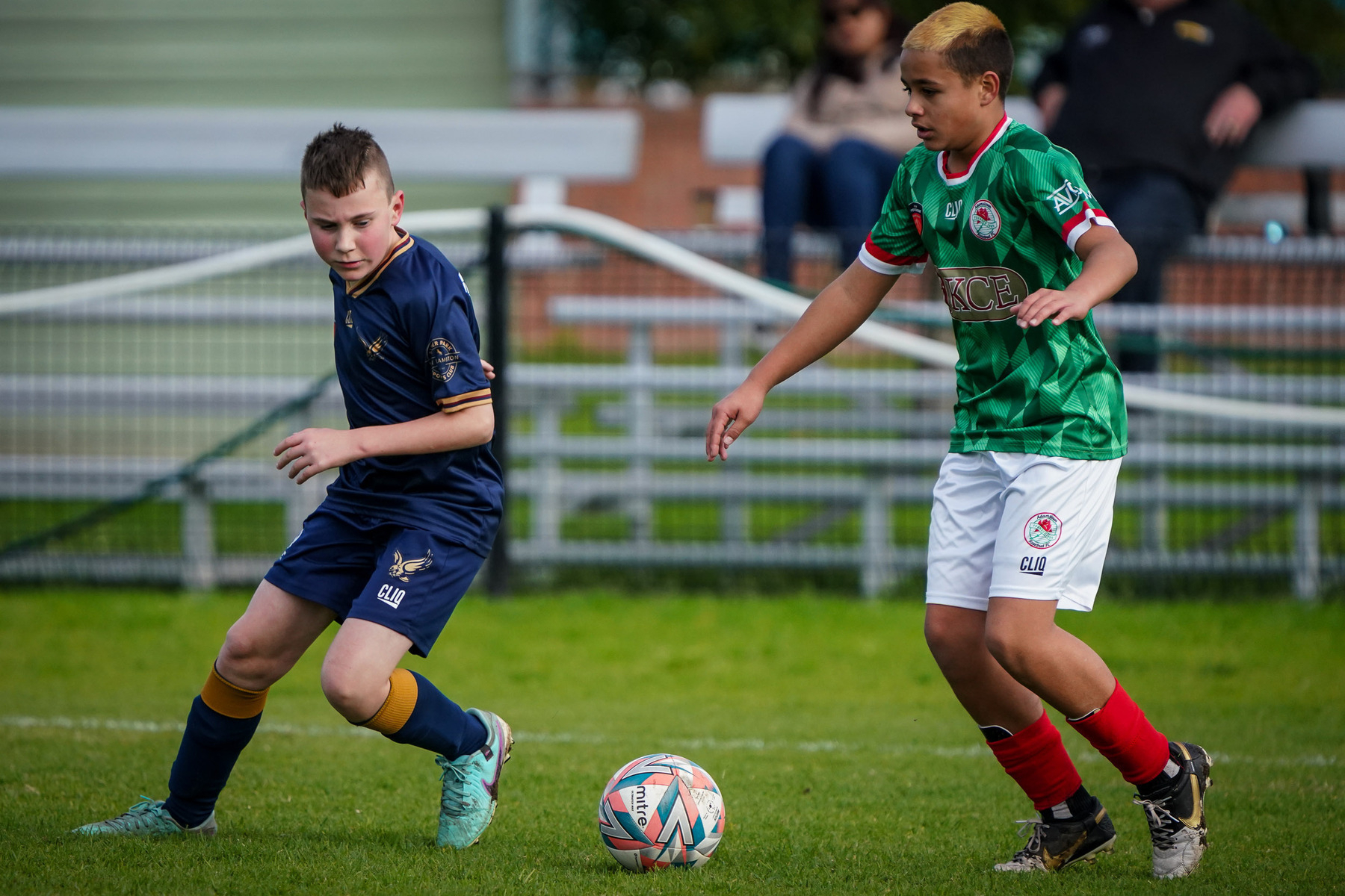 Two young soccer players compete for the ball on a grassy field.