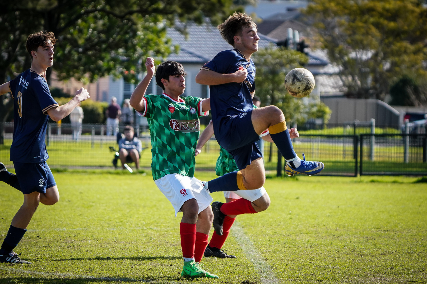 Two soccer players are actively engaged in a game, with one player jumping to control the ball.