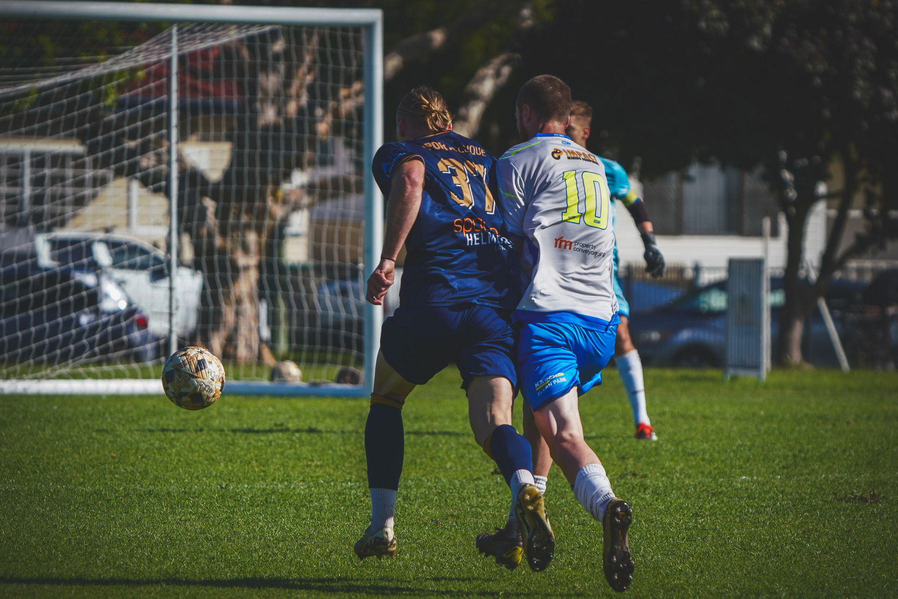 Two soccer players are competing for the ball during a match on a grassy field.