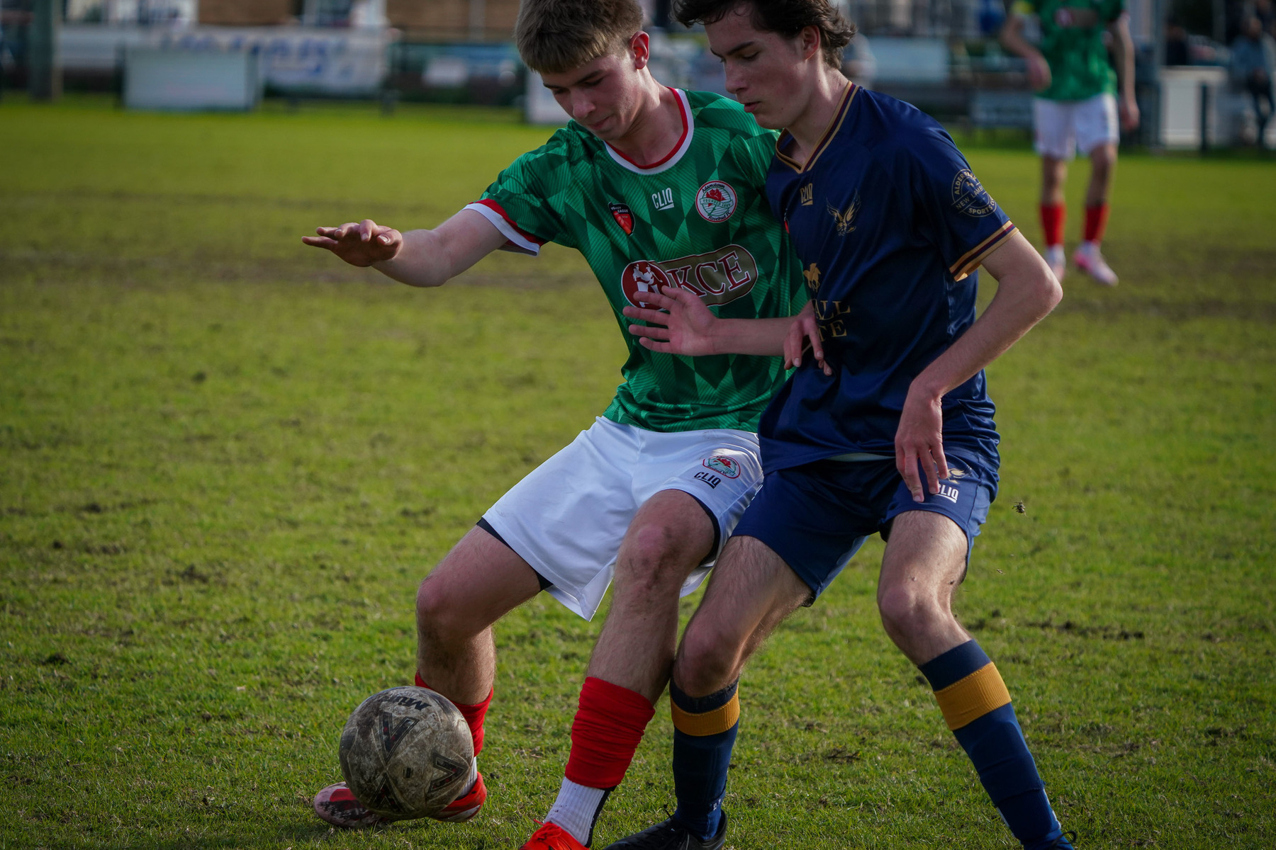 Two soccer players are competing for control of the ball on a grassy field.