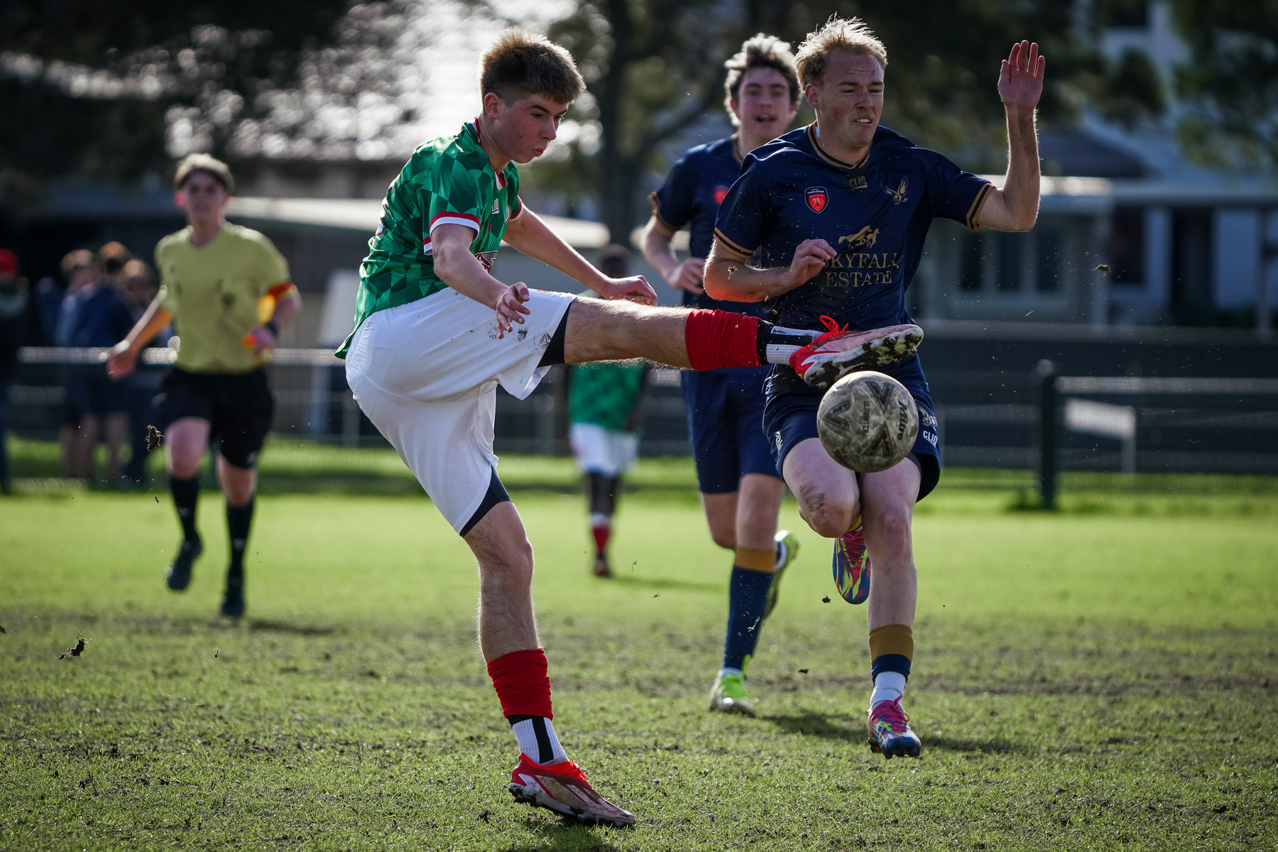 Two soccer players compete for the ball during a match, with one player attempting a high kick.