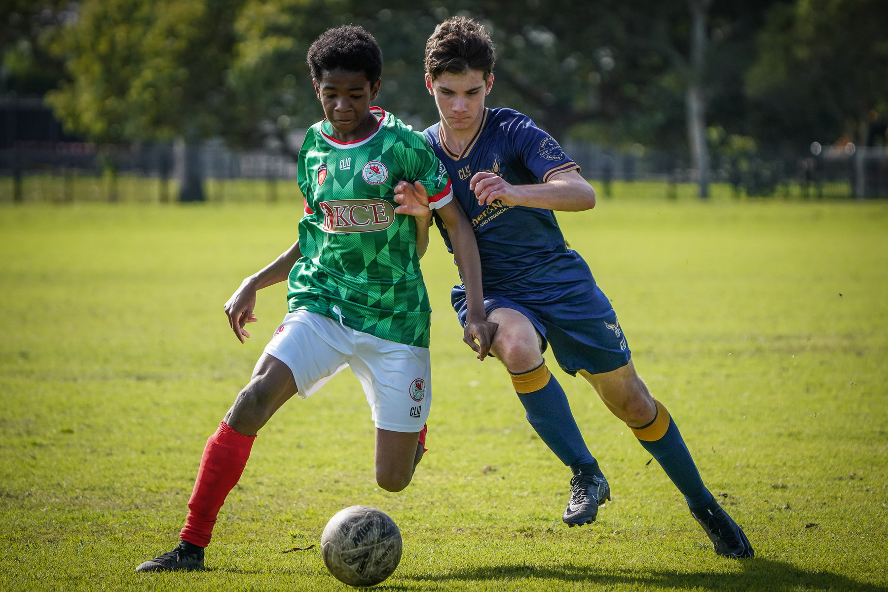 Two soccer players are competing for the ball on a grassy field.