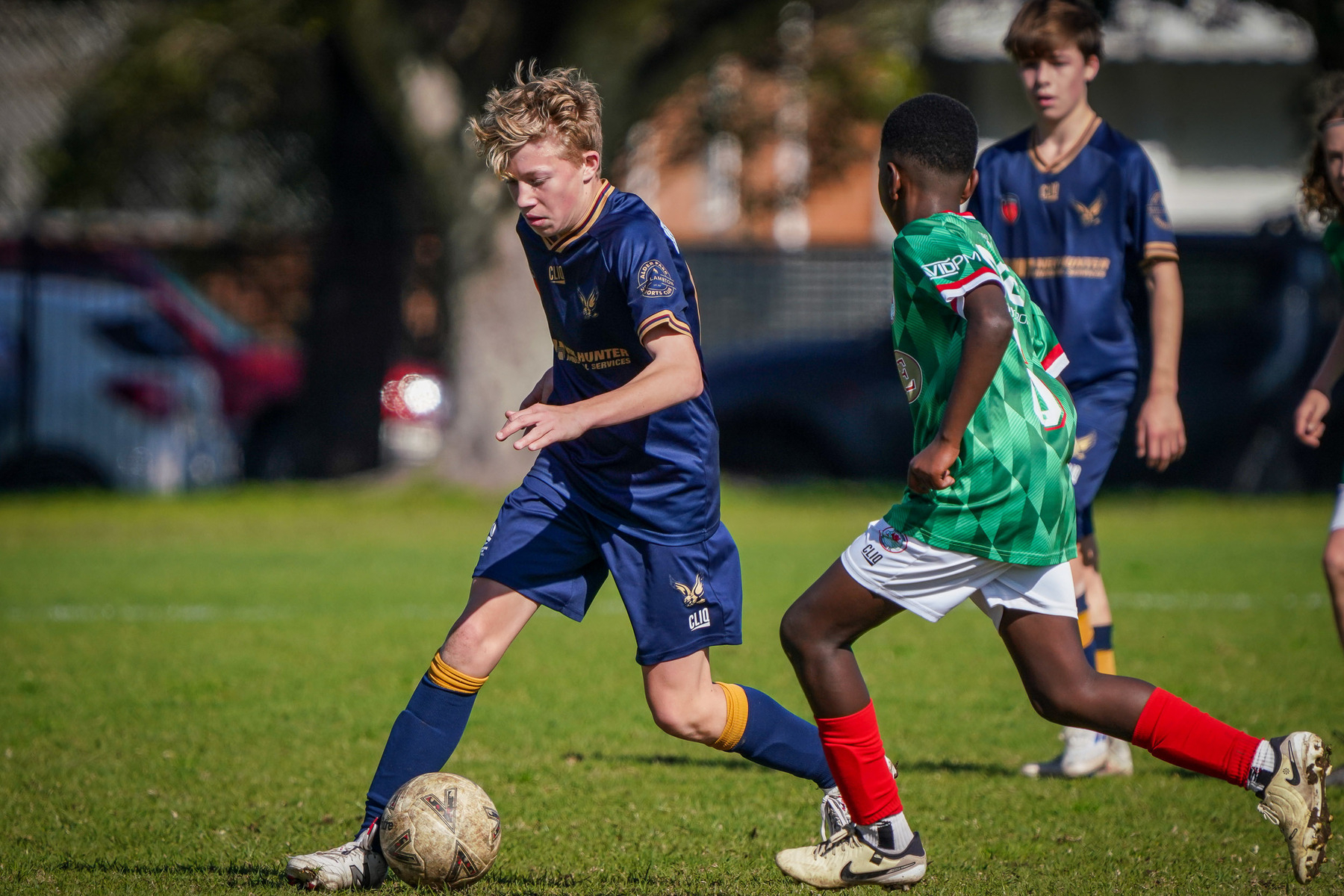 A youth soccer game is in action with players from two different teams competing for the ball.