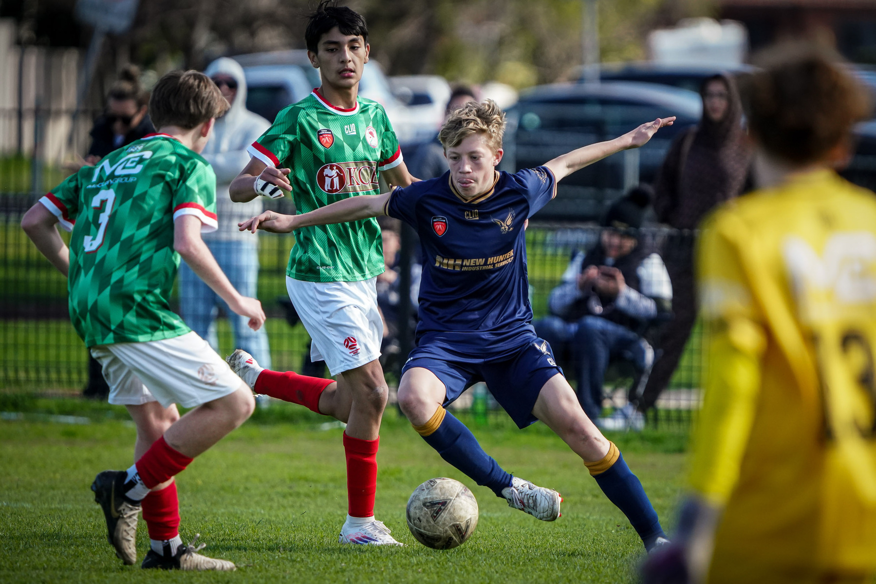 A group of young soccer players actively competes on the field, focusing on gaining control of the ball.