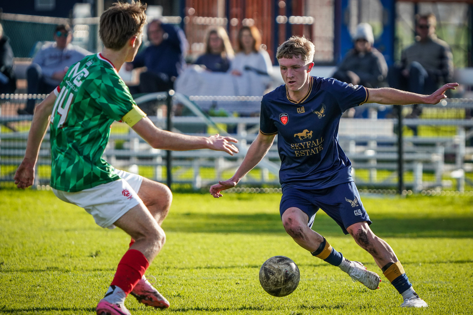 Two soccer players are actively competing for the ball on a grassy field during a match.